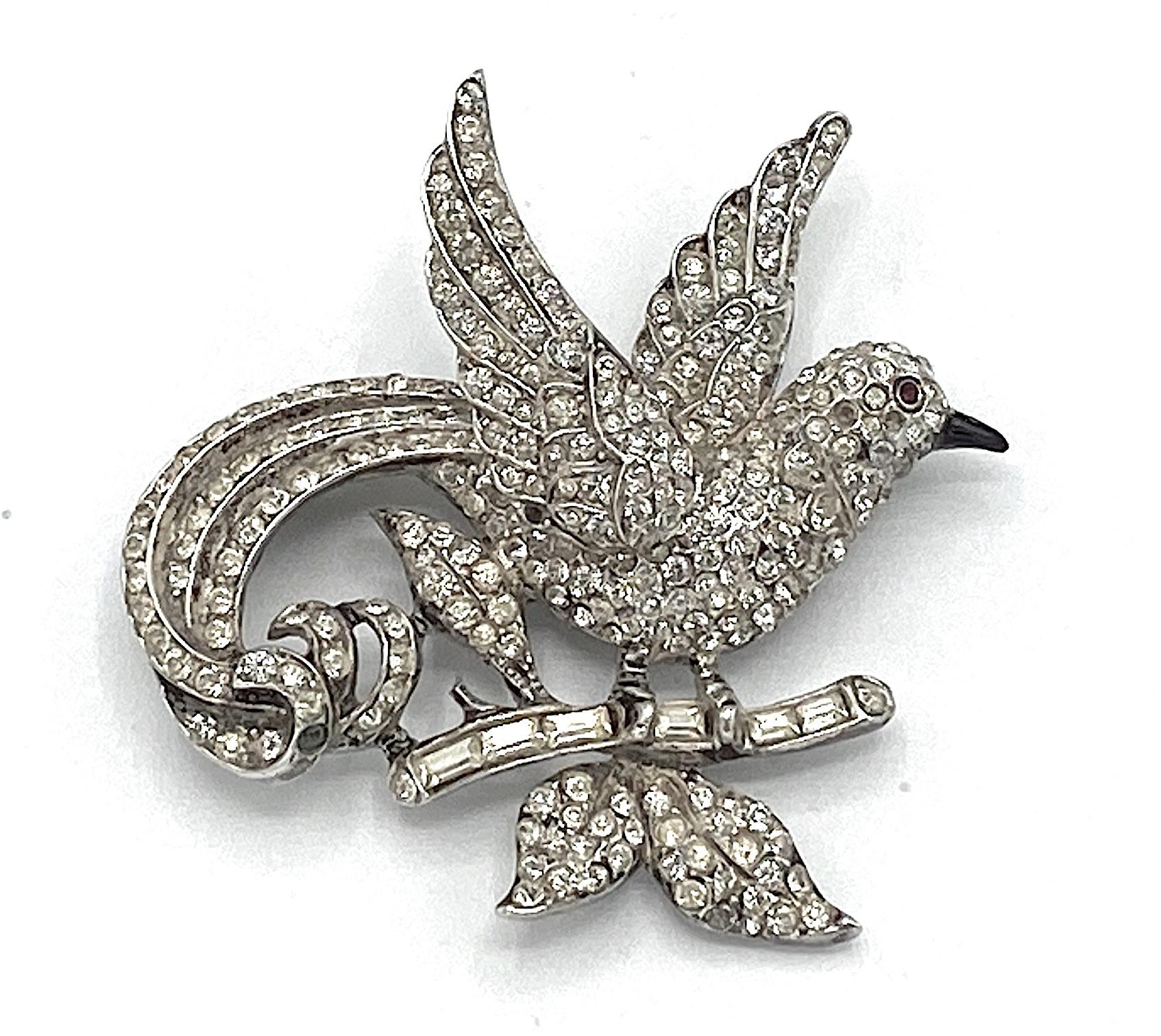 A collectable and charming 1940s brooch of a bird flying with a branch in its claws by famous American fashion jewelry company Coro. Coro was the larges produce of fashion jewelry and operated from 1901 to 1978. The brooch is rhodium plate on