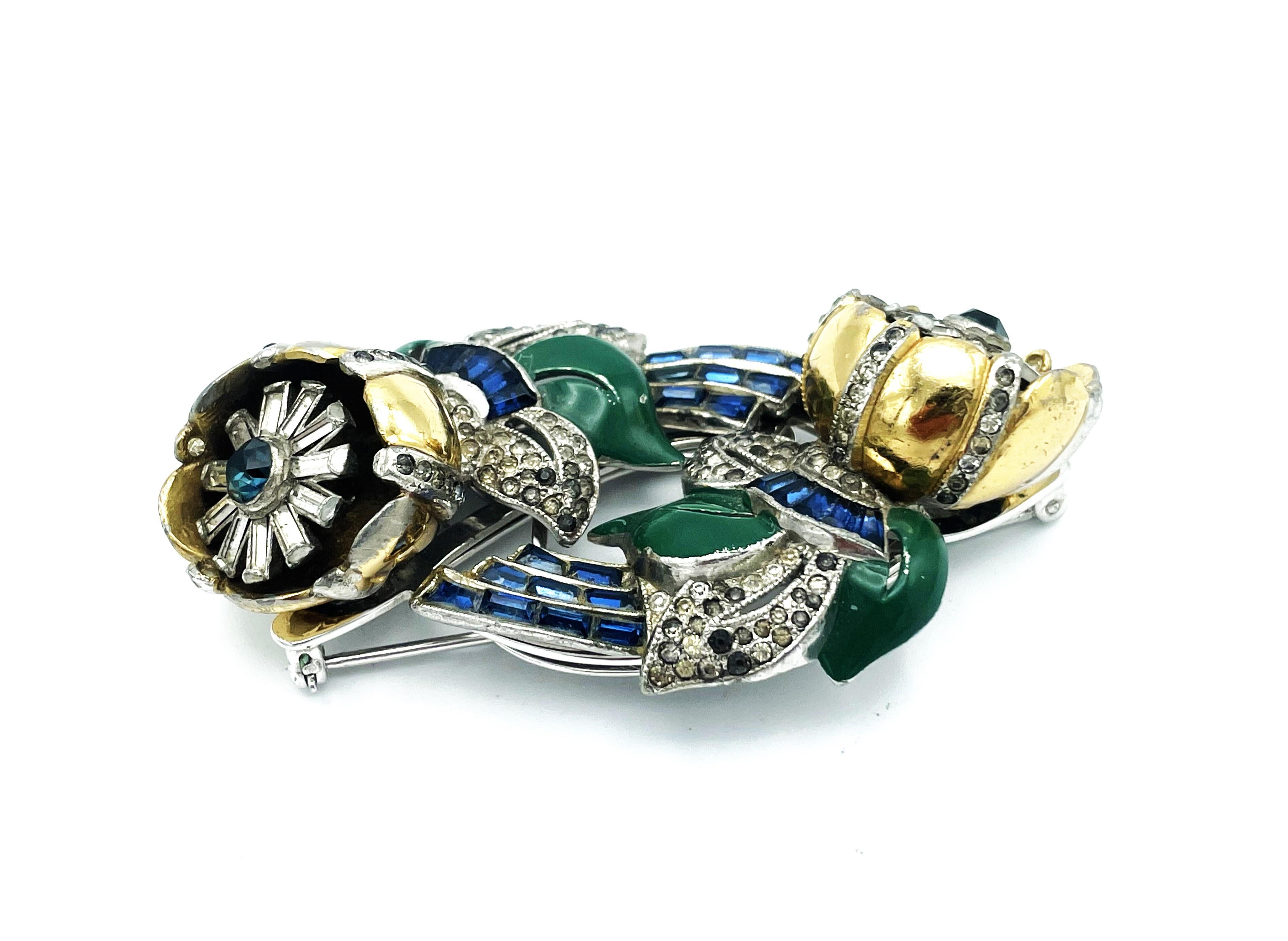 Coro classic flower twist Duett brooch of gilt metal, green emamal leafs, blue crystal baguette crystal stones and many small crystal pastes. Both flower clips separate off base to be worn separately.  Designed in USA in the 1940s, good Condition -