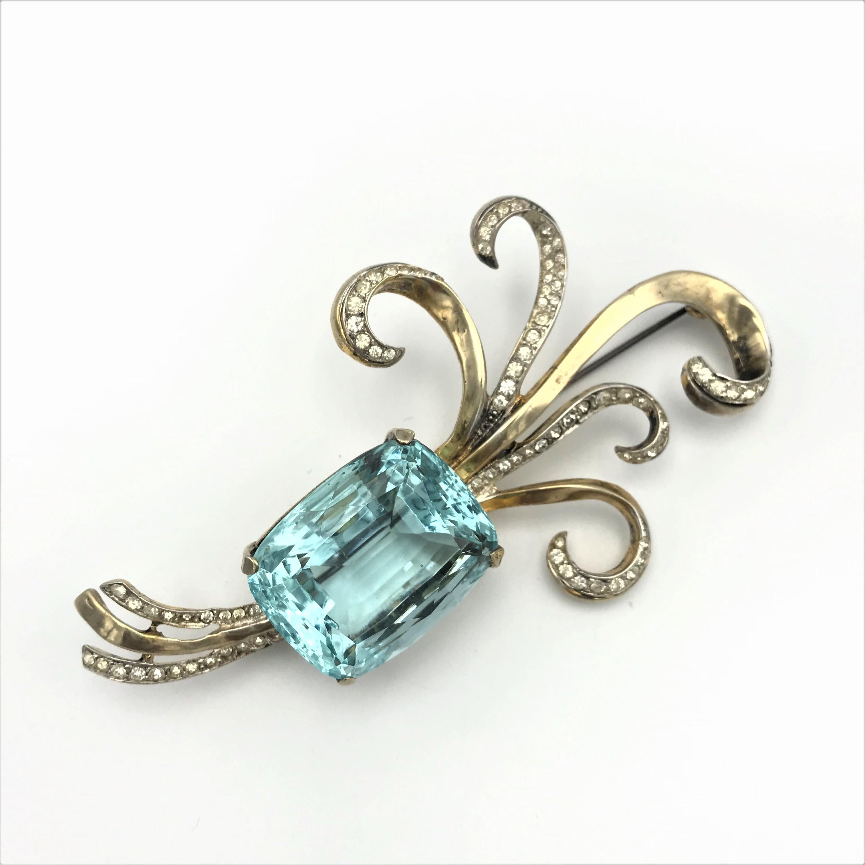 A typical brooch from the 1940s with a large false cut aquamarine, designed by Adolf Katz in the USA.  Gold plated Sterling, rhinestones around the swirl and singed at the backside with 'Corocraft Sterling' 
Measurement:  Length 10 cm, Width 5,5 cm,