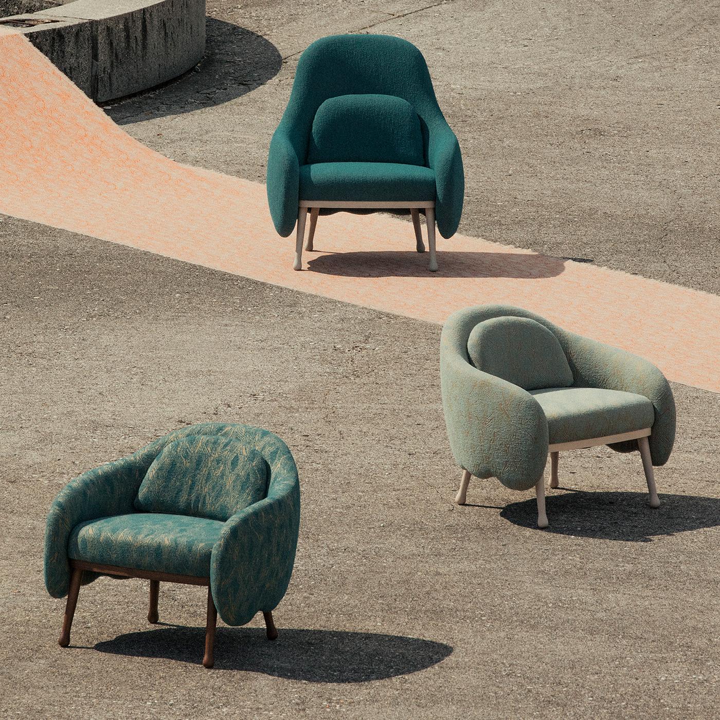The delicate shape of flower corollas inspired this splendid armchair from the Corolla series, stunning in its scalloped lower profile, which seals the contours of the enveloping seat also incorporating the sloping armrests. The slanted legs in