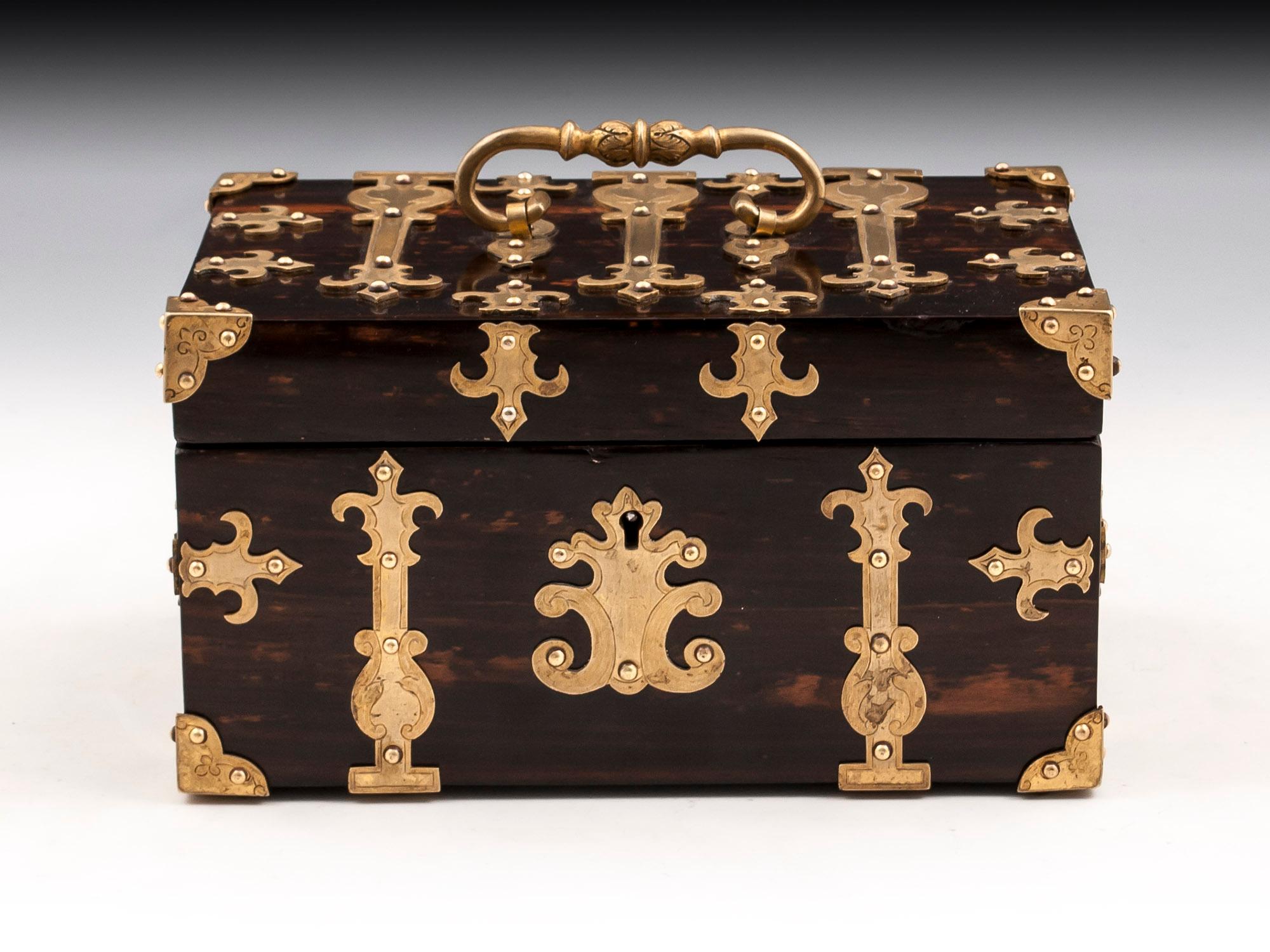 Antique Coromandel trinket box with ornate engraved applied brass mounts, corner brackets, carry handle and escutcheon. 

The interior is lined in vibrant marble effect paper with a cushioned velvet pad for the base. 

This antique trinket box
