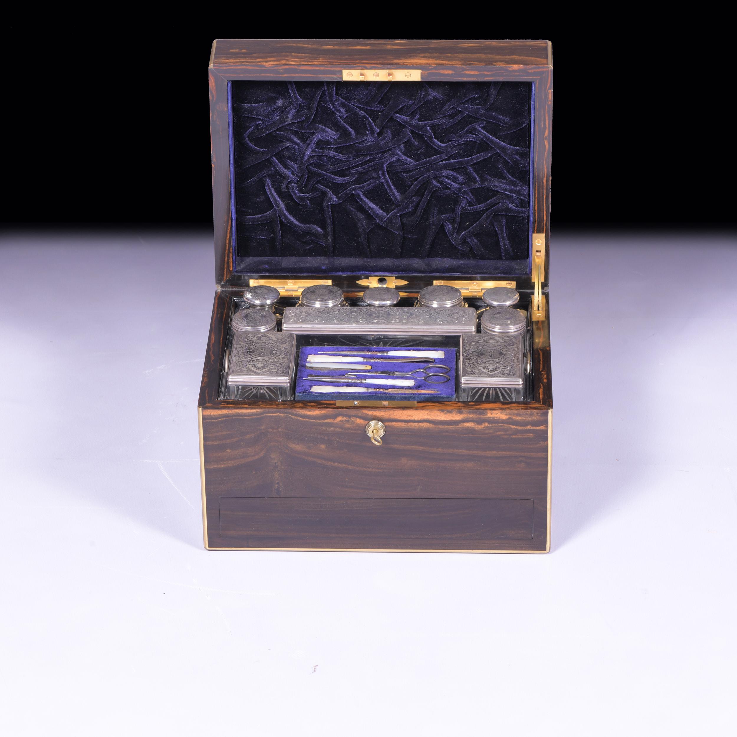 An exceptional quality coromandel and brass mounted lady's vanity / dressing case and cover. Having fully fitted interior which features 10 silver lidded glass containers by Betjemanns & Sons of London. With a fitted tool pad with various Mother of