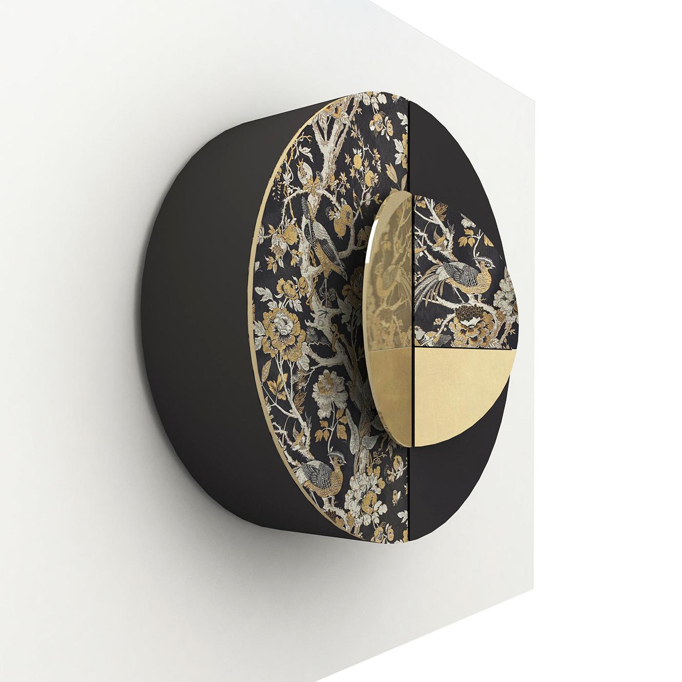 Named after the renowned Chinese screen of the XVII and XVIII century, this piece is a sculptural objet d'art that functions as wall cabinet. Boasting a black and white color palette, its round wooden structure is partially upholstered with a