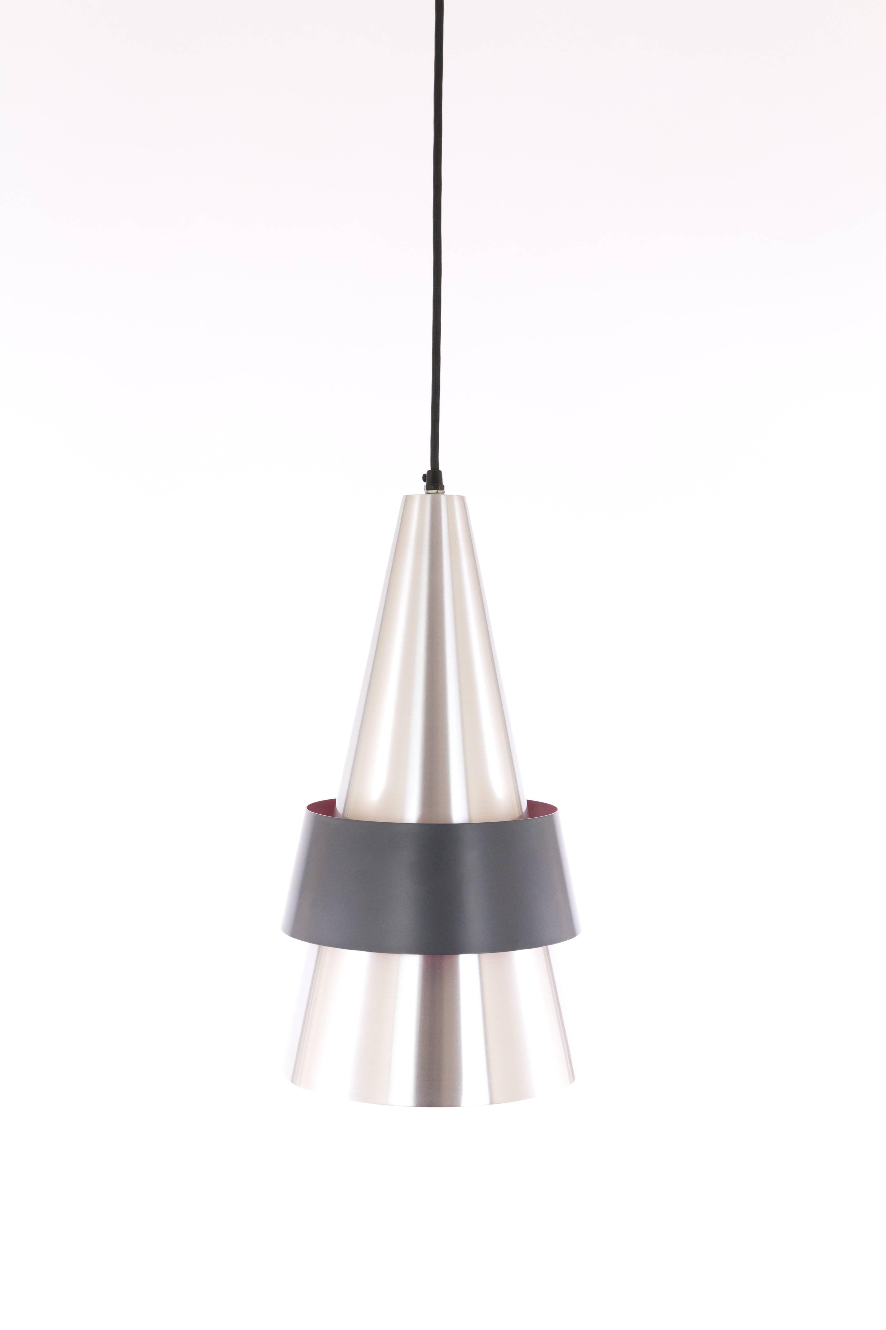 Pendant designed in the early 1960s by famous Danish designer Jo Hammerborg. Corona was one of his earlier designs for Fog & Mørup.

The cone of solid satin aluminium consists of two parts and is held together by a black lacquered band. The inside