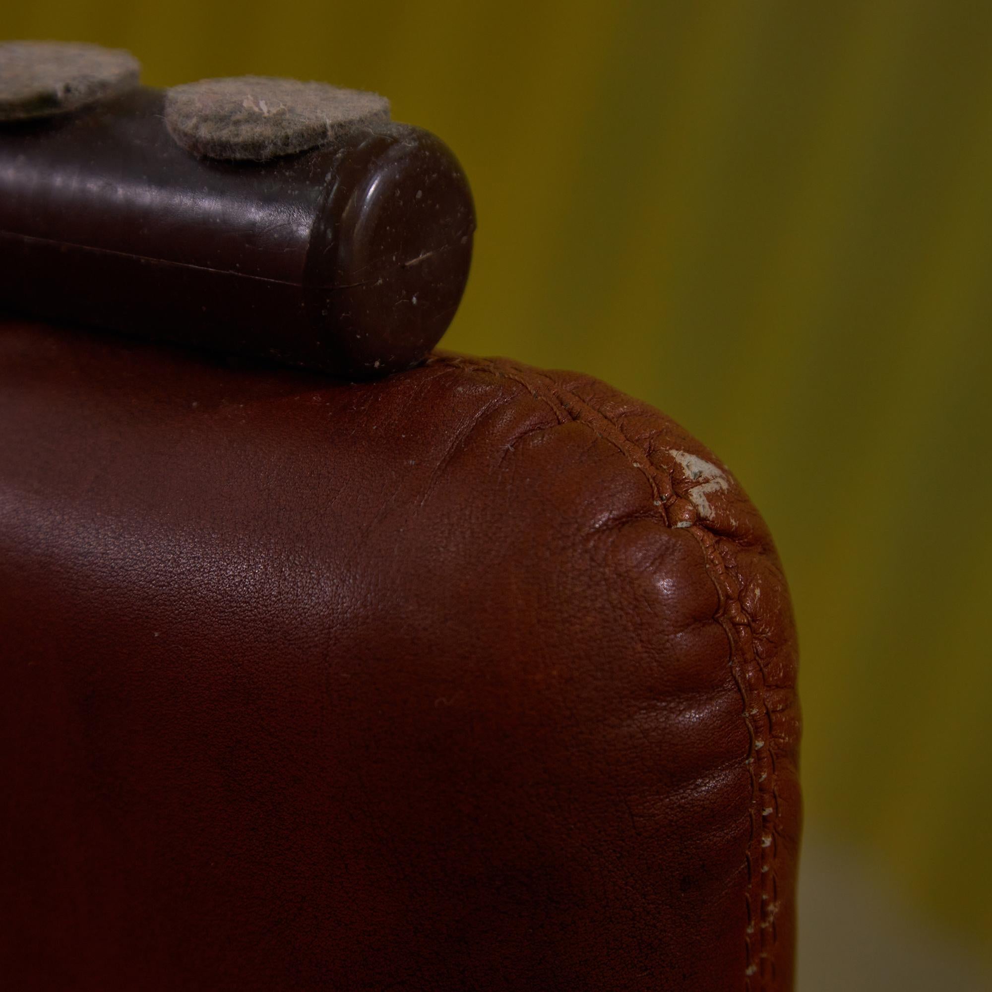 Introducing the iconic Coronado armchair, a stunning creation by the renowned design duo Afra & Tobia Scarpa for B&B Italia in the 1960s. Wrapped in luxurious warm brown leather, this high-back armchair and its matching ottoman offer the ultimate in