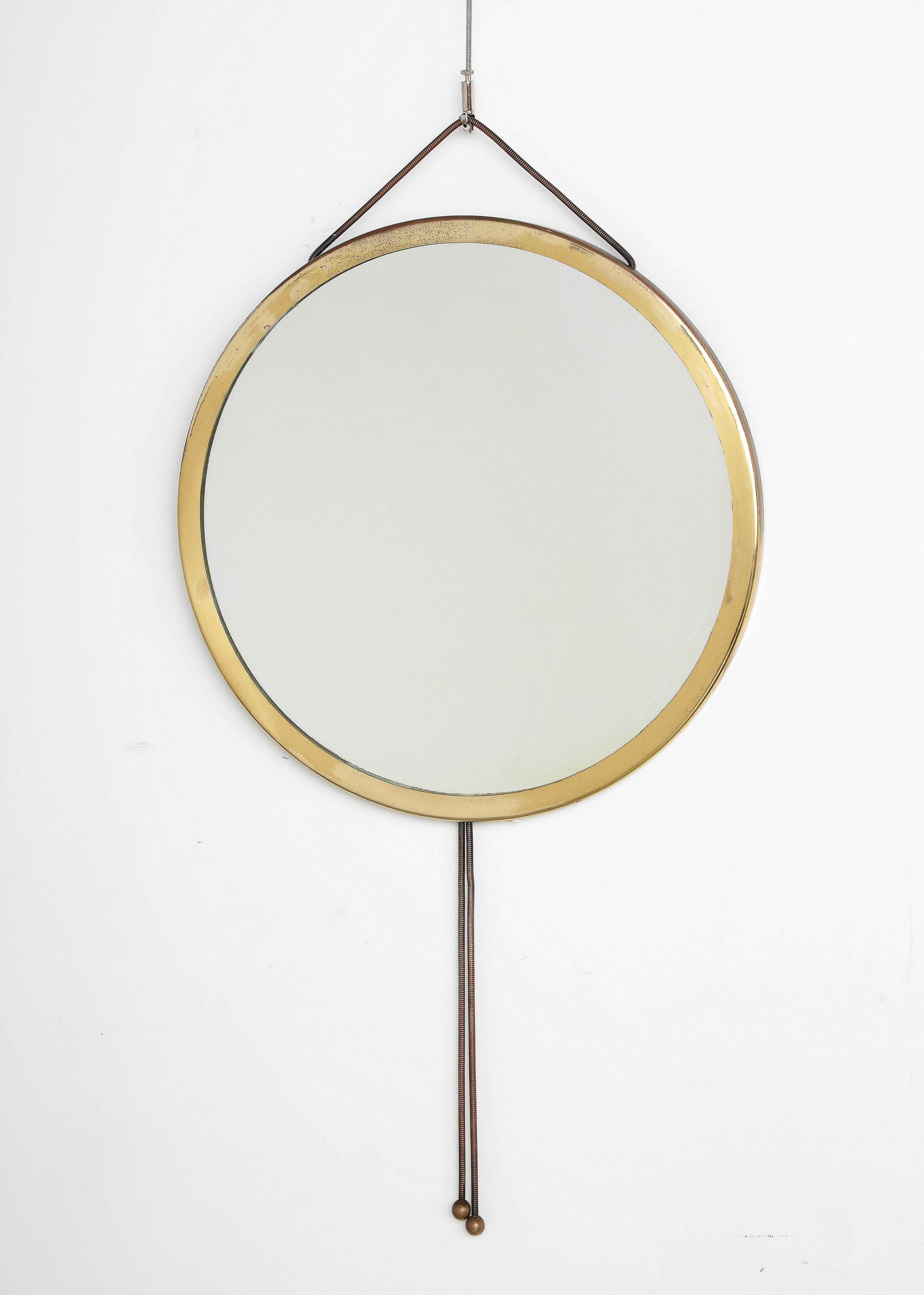 A circular brass wall mirror, designed by Corrado Corradi Dell' Acqua for Azucena, circa 1960.  The brass molded circular frame is hung with a cord on top which attaches to the back wood frame and is adjustable, the cord culminates in tassels in