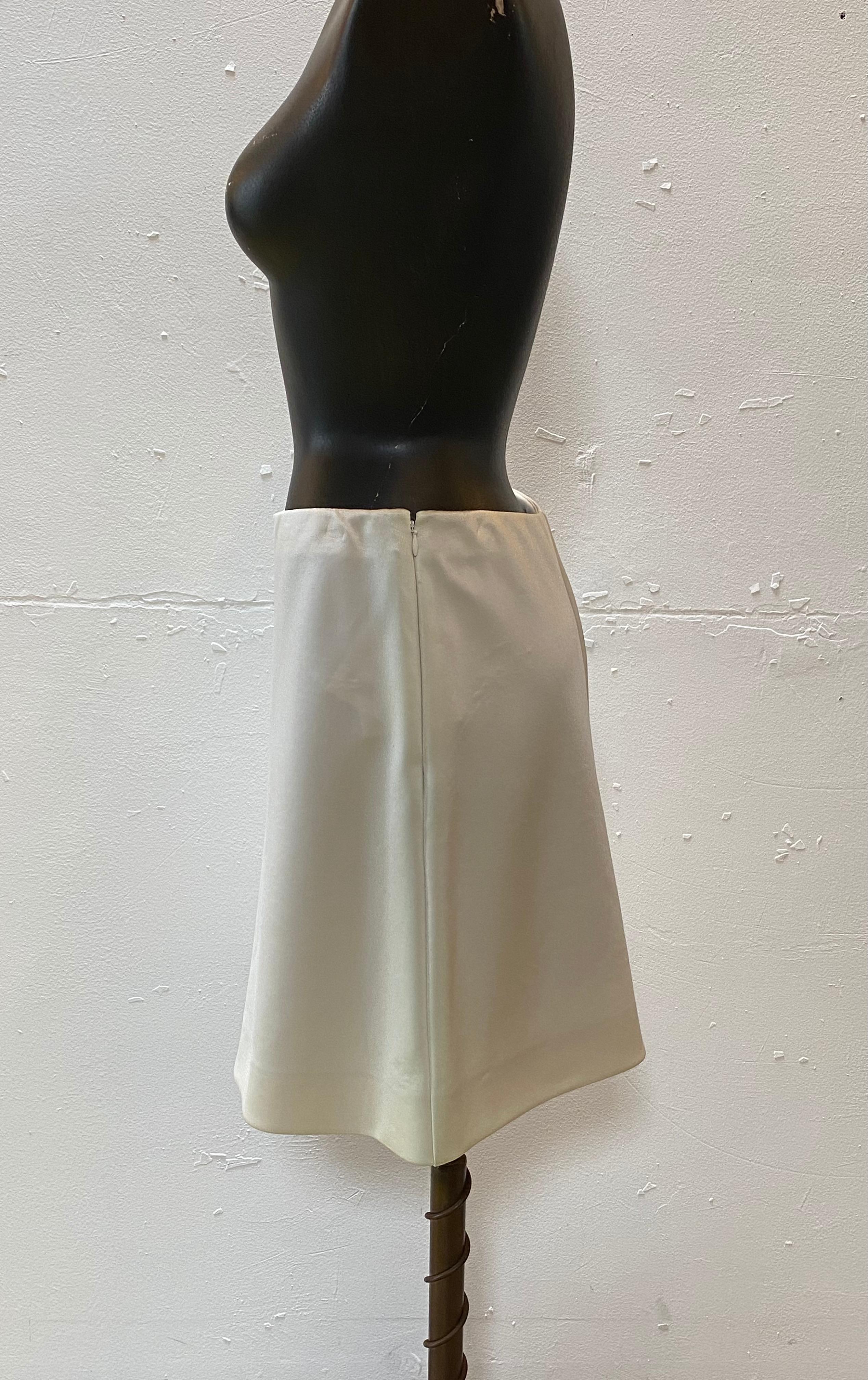 Satiny soft Correges short skirt in milk-color fastens with a side zip. 