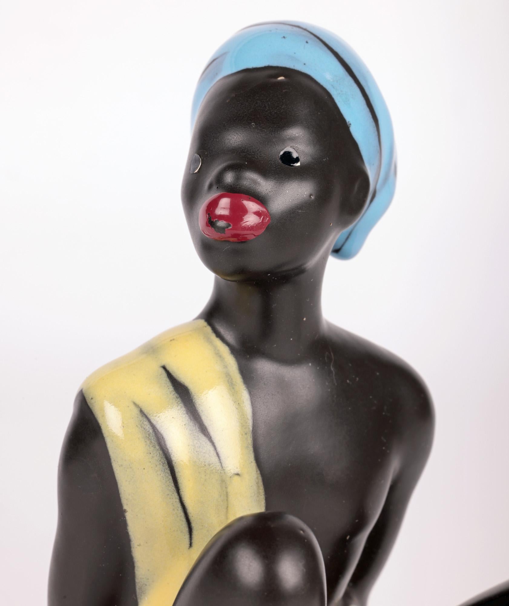 Une élégante figure ouest-allemande du milieu du siècle représentant un homme africain assis, par Cortendorf. La figurine en poterie repose sur une base arrondie avec un bord arrière plat et représente un homme assis reposant sur ses bras, les