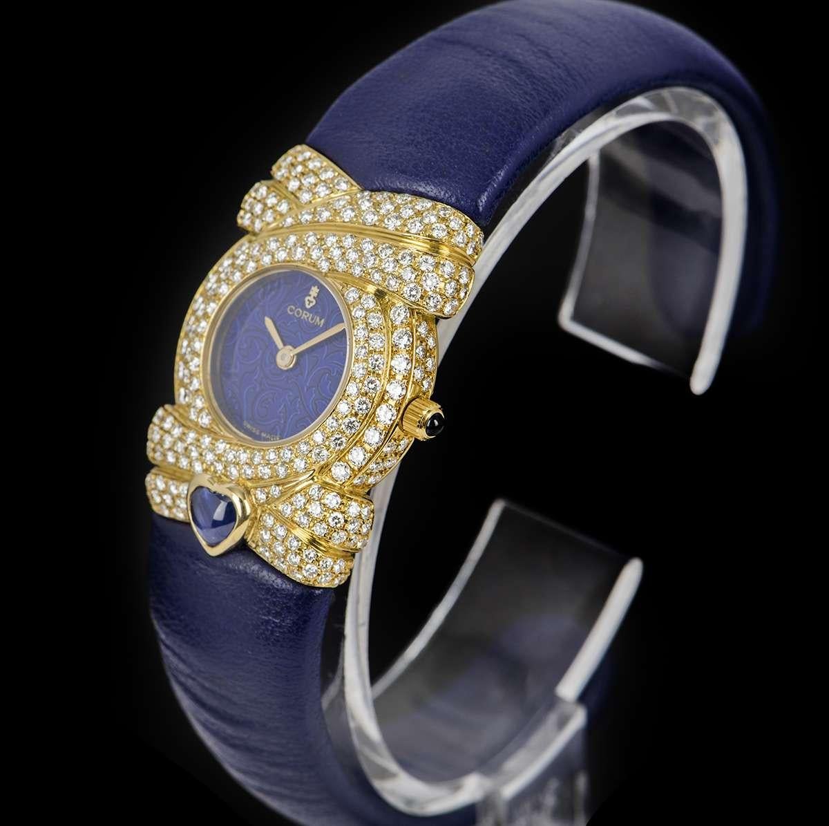 An Unworn 18k Yellow Gold Ladies NOS Dress 22mm Watch, blue dial with filigree design, 18k yellow gold bezel, lugs and case set with approximately 246 round brilliant cut diamonds (~1.86ct), an original blue leather cuff, sapphire glass, quartz