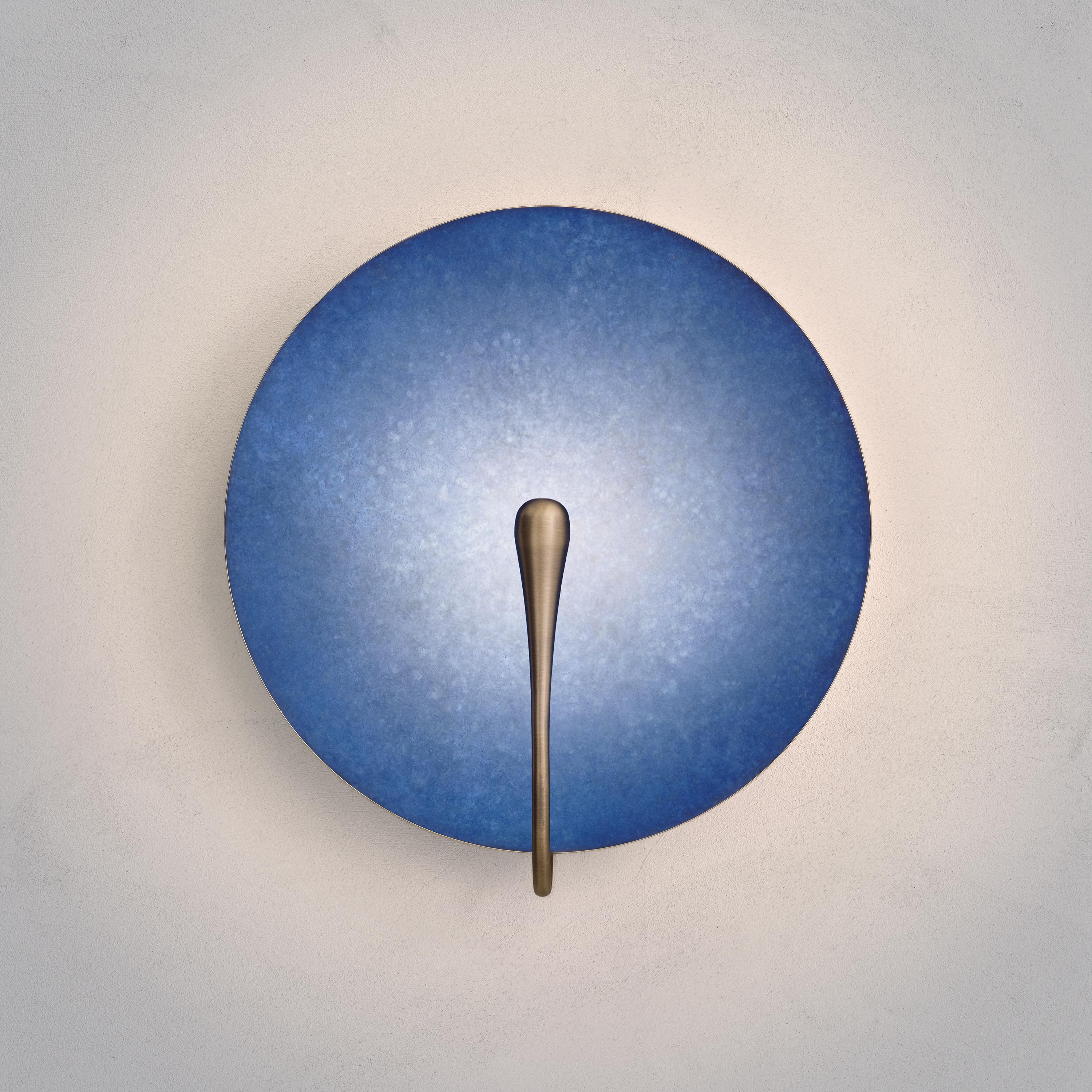 Inspired by the beautiful textures of nature, a bright indigo patina is applied on a hand-spun brass plate to create this unique finish.
 
Softly illuminated with integrated LED from within, this sculptural wall piece sits elegantly in both