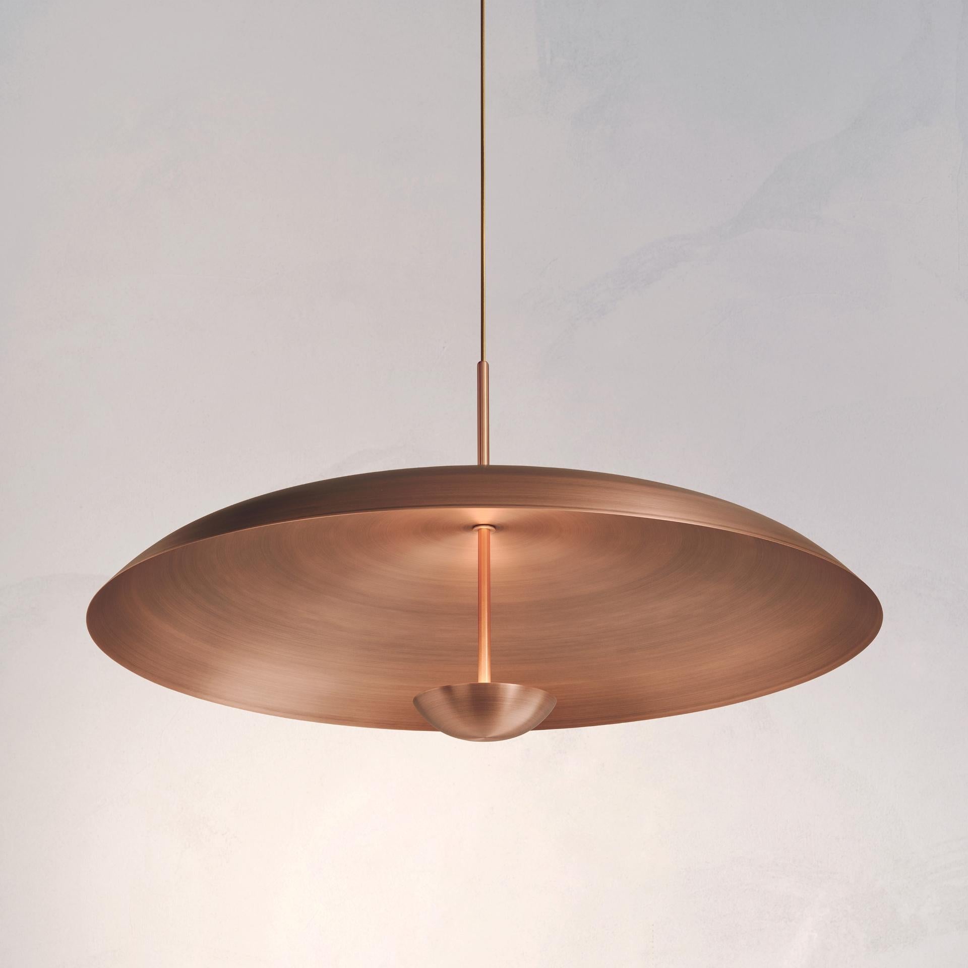 Two finely hand-spun copper plates make up this pendant light,  finished in a bronze patina to create this unique appearance. The light is projected into the shade and reflects out, illuminating without creating a glare.
 
This light fixture is