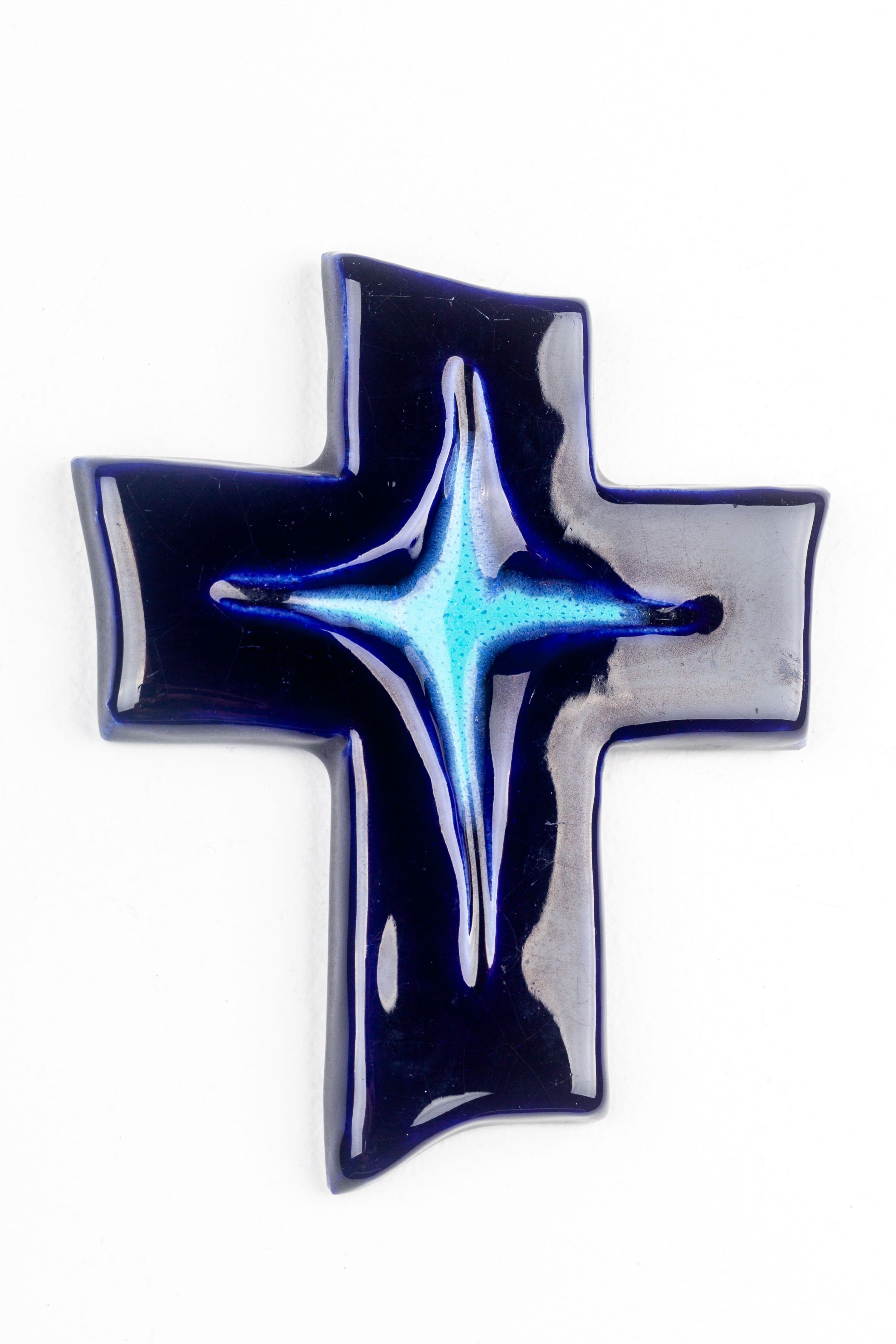 This ceramic cross exemplifies the innovative spirit of mid-century European studio pottery, marrying traditional religious symbolism with a distinctly modern aesthetic. The handcrafted piece features a deep, midnight blue glaze that evokes the