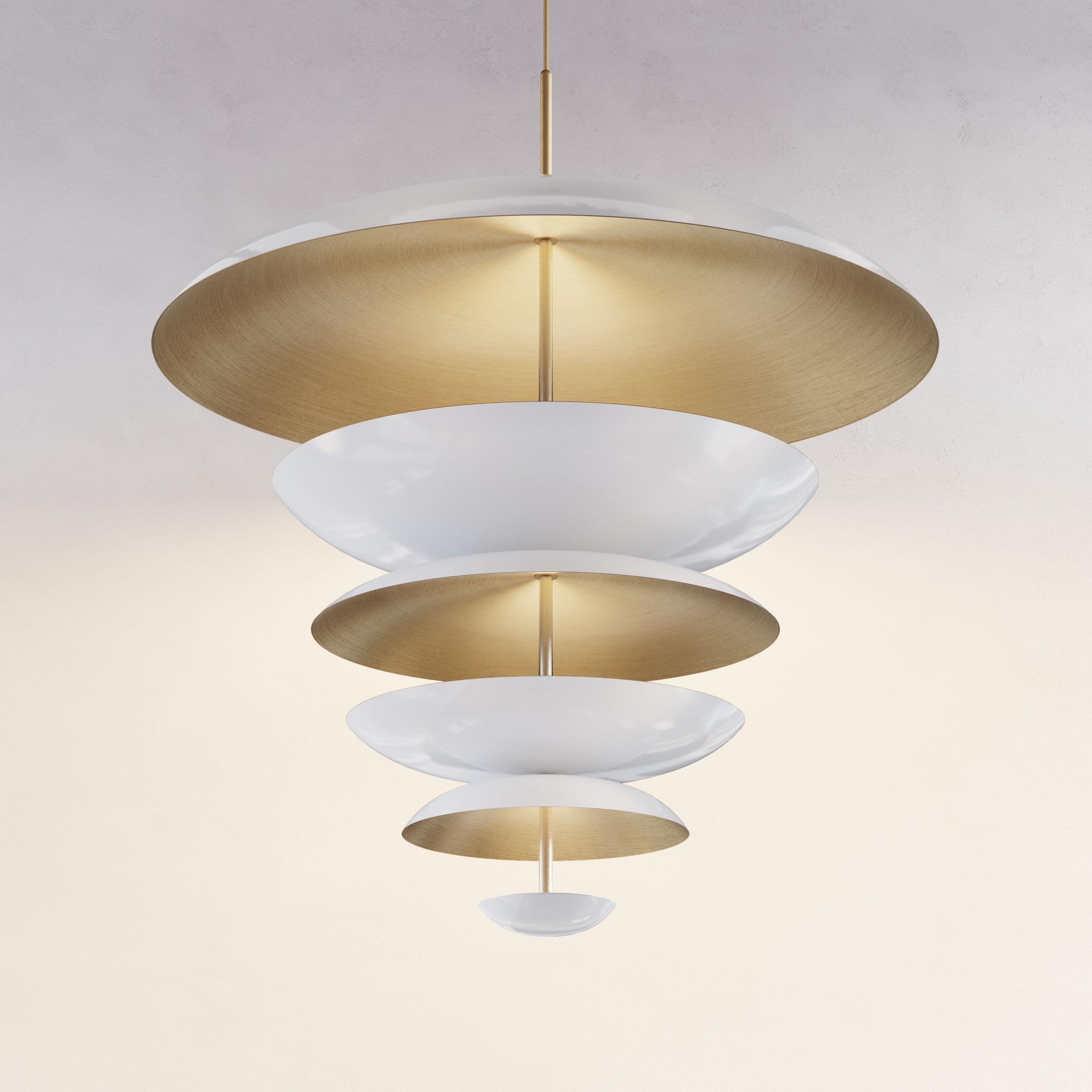 Finely hand-spun brass plates make up this pendant light. One side is finished in either a gloss white or matt white piano lacquer and the inside finely brushed brass. The light is projected into the shade and reflects out, illuminating without