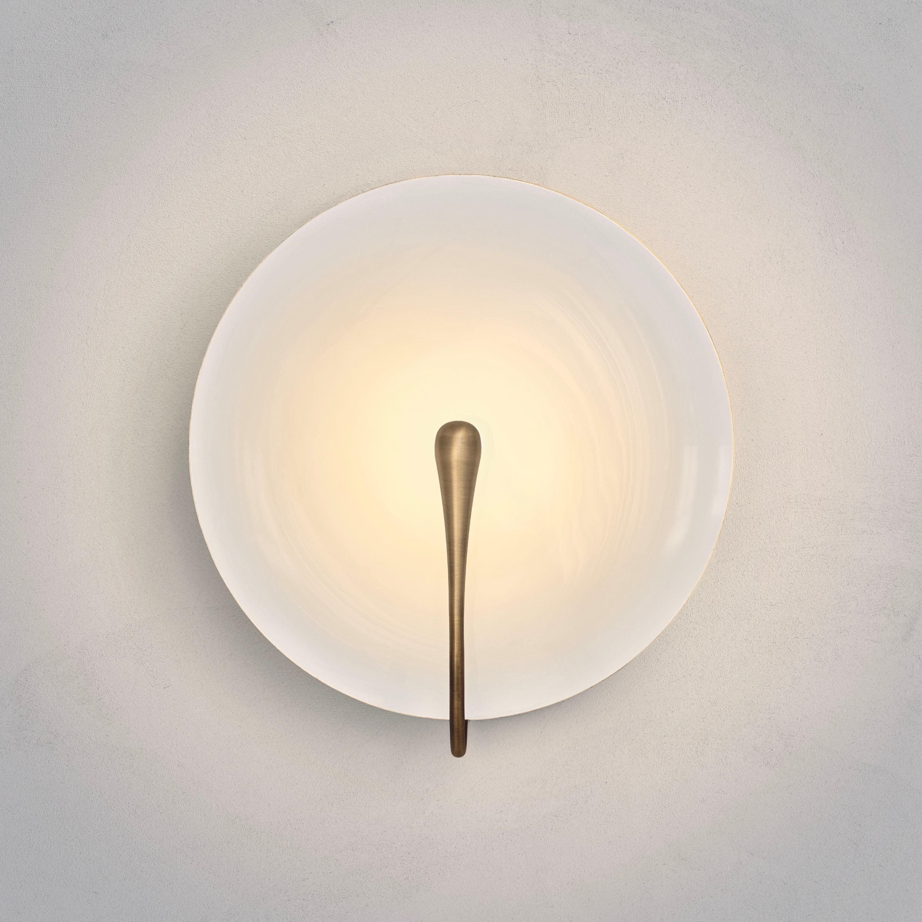 A gentle silhouette of a plate makes up this unique wall light. The back and edges of the brass shade are kept in original brass whilst the inner surface is hand-lacquered to create a gloss or matt white finish. Please note that with each process