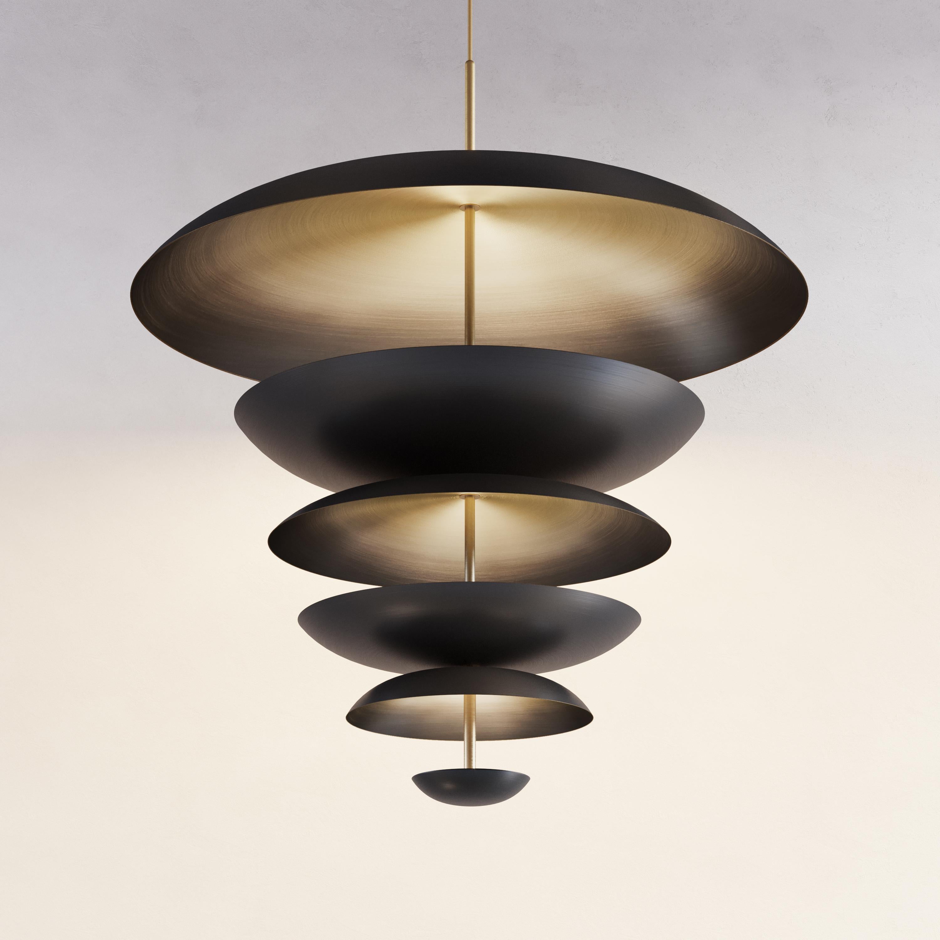 Finely hand-spun brass plates make up this pendant light. One side of the shade is finished in a dark bronze patina and the other in a gently brushed brass gradient. The light is projected into the shade and reflects out, illuminating space without