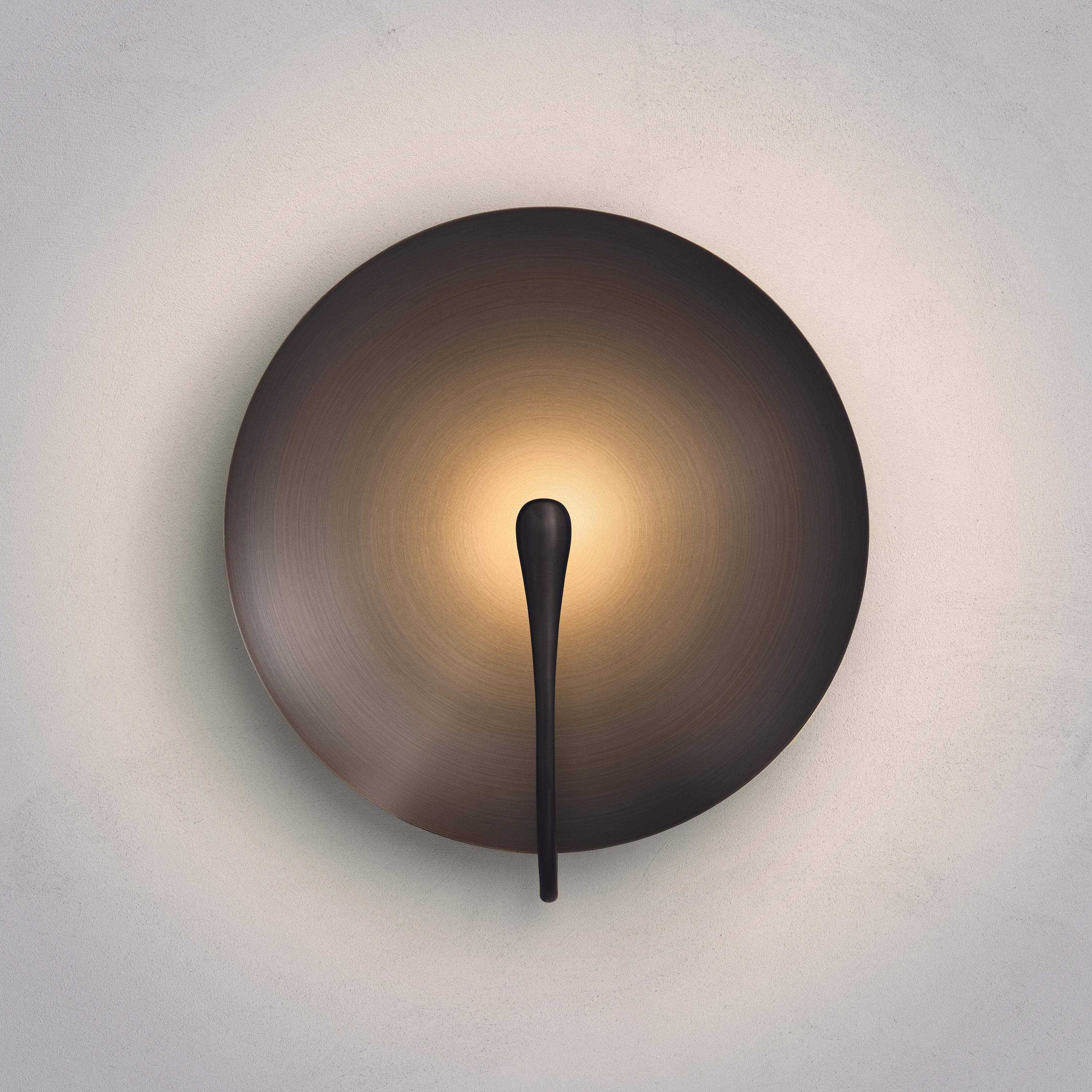 A gentle silhouette of a plate makes up this unique wall light. To create this metalic finish, a dark bronze patina is applied on a hand-spun brass plate. Please note that with each process being slightly random, every result is variant.
 
Softly