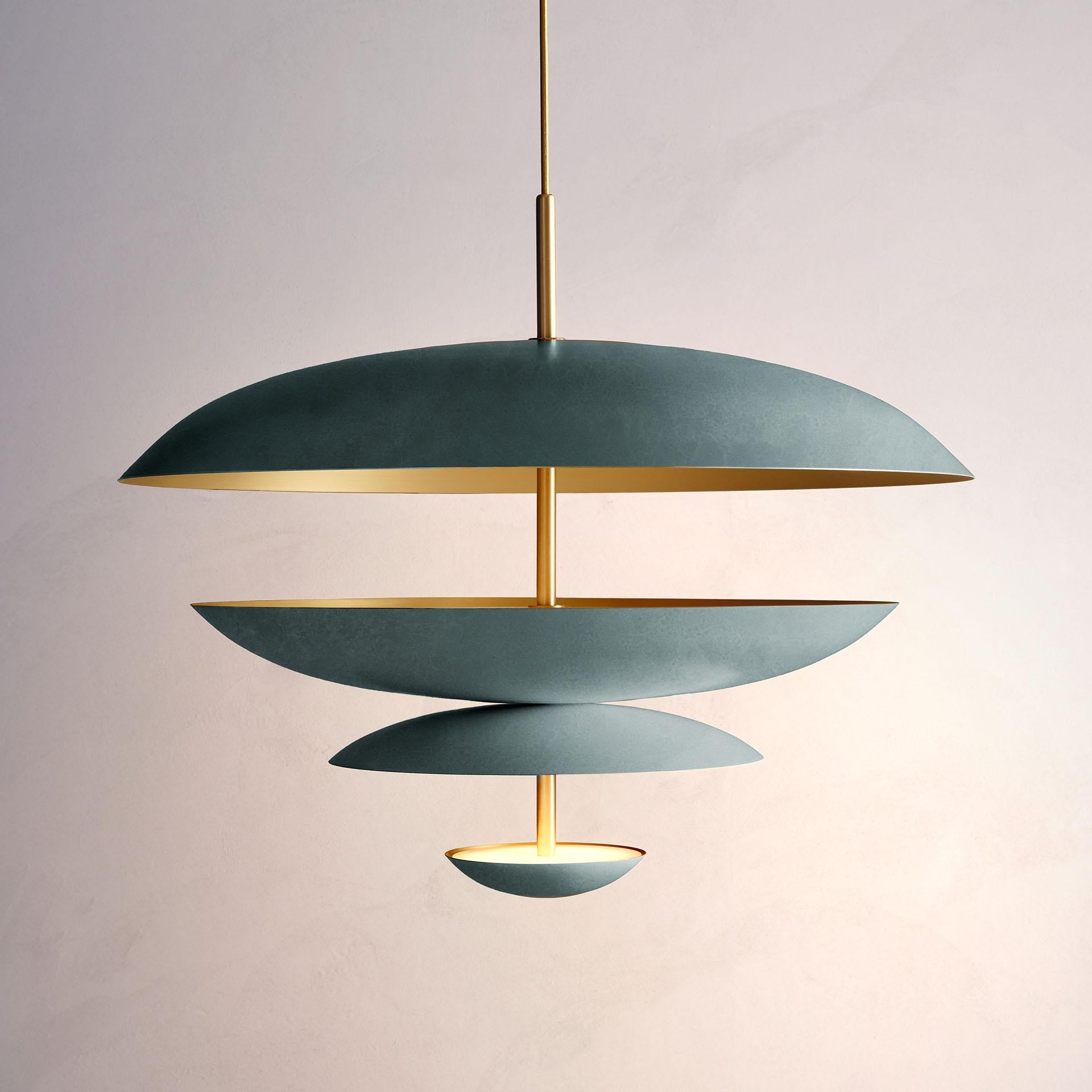Composed by four finely hand-spun brass plates, this chandelier is finished in a verdigris patina on one side and satin brushed brass on the other to reveal the bright texture of brass. Light is projected into the shade before reflecting out,