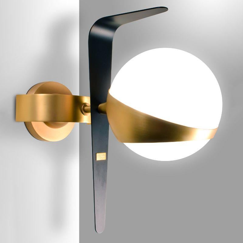 An iconic, futuristic-like design, this wall lamp will make a stunning addition to a refined contemporary interior. Fashioned of brass combining gold and black lacquers, it features a luminous spherical shade. Please inquire for more information on