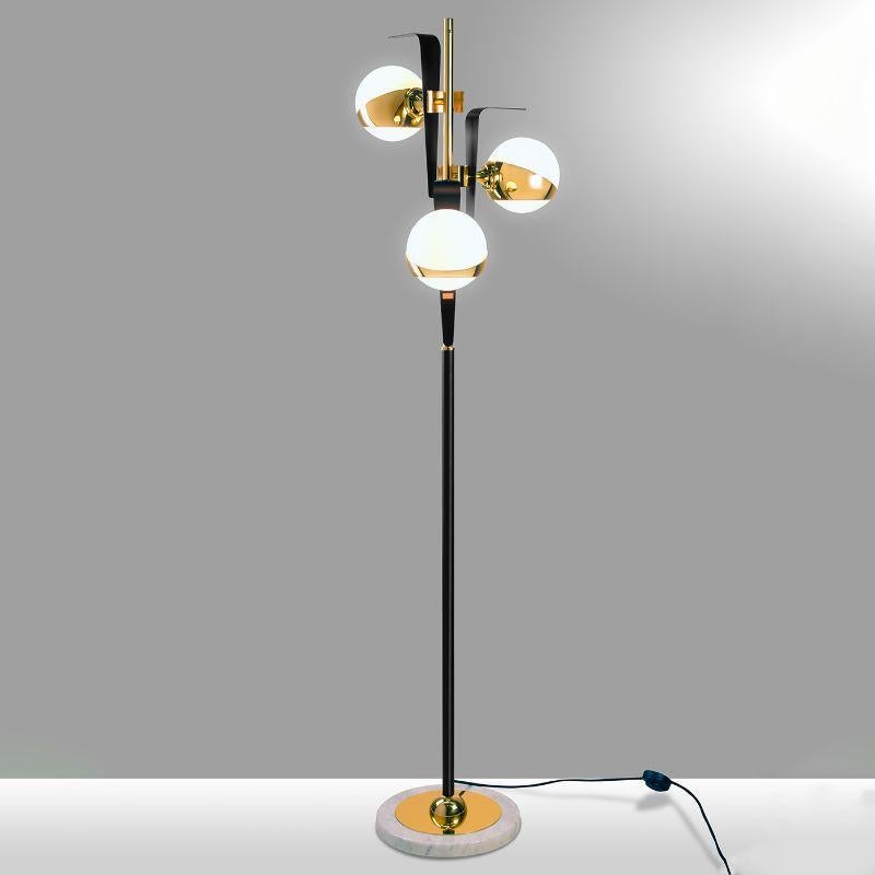 Incredibly sleek and refined in its linear design, this stupendous floor lamp will take center stage in a refined contemporary interior. Fashioned of black and gold-lacquered brass, it rests on a white marble base and features three stunningly