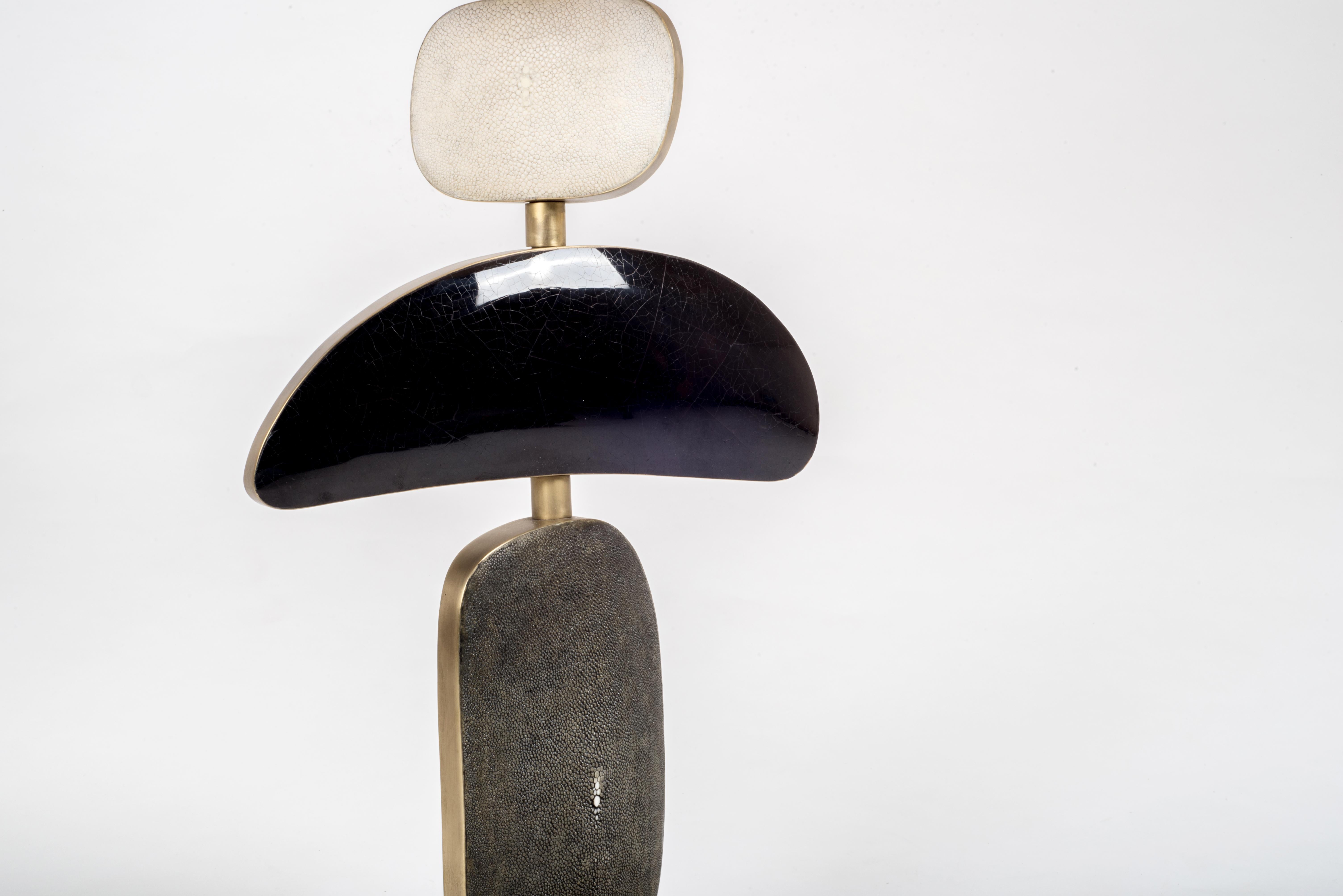 La lampe de table Cosmo de Kifu Paris est une pièce fantaisiste et sculpturale, incrustée de crème, de coquille noire et de noir avec des accents de laiton bronze-patiné. Les formes amorphes de la partie inférieure peuvent être déplacées pour