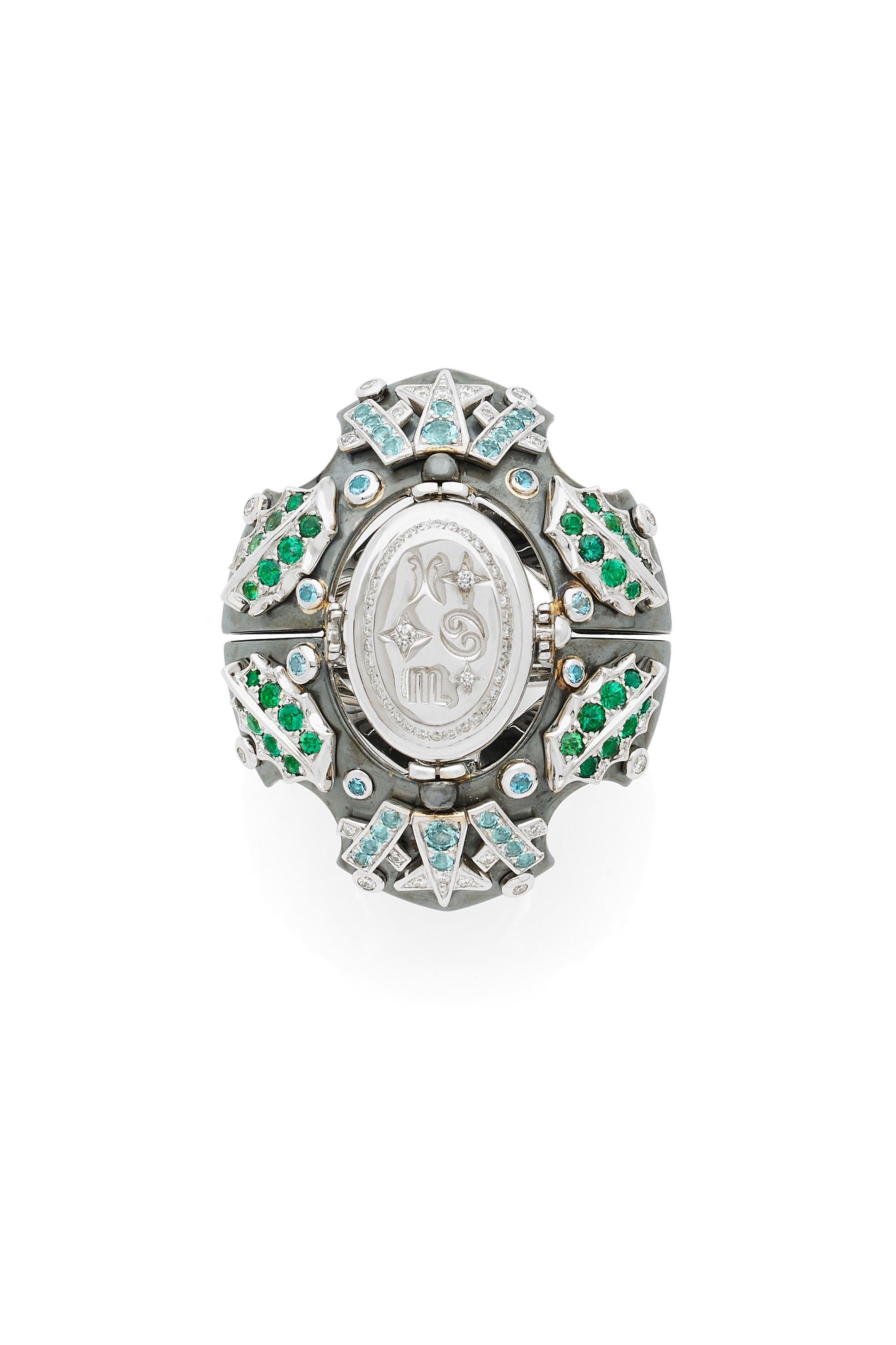 White gold and distressed silver ring.  Set with diamonds, yellow sapphires, garnets, and tsavorites. Rotating medallion: on the white gold are engraved zodiac signs and on  the chalcedony, a green tourmaline.

Details:
Chalcedony
Yellow Sapphires,