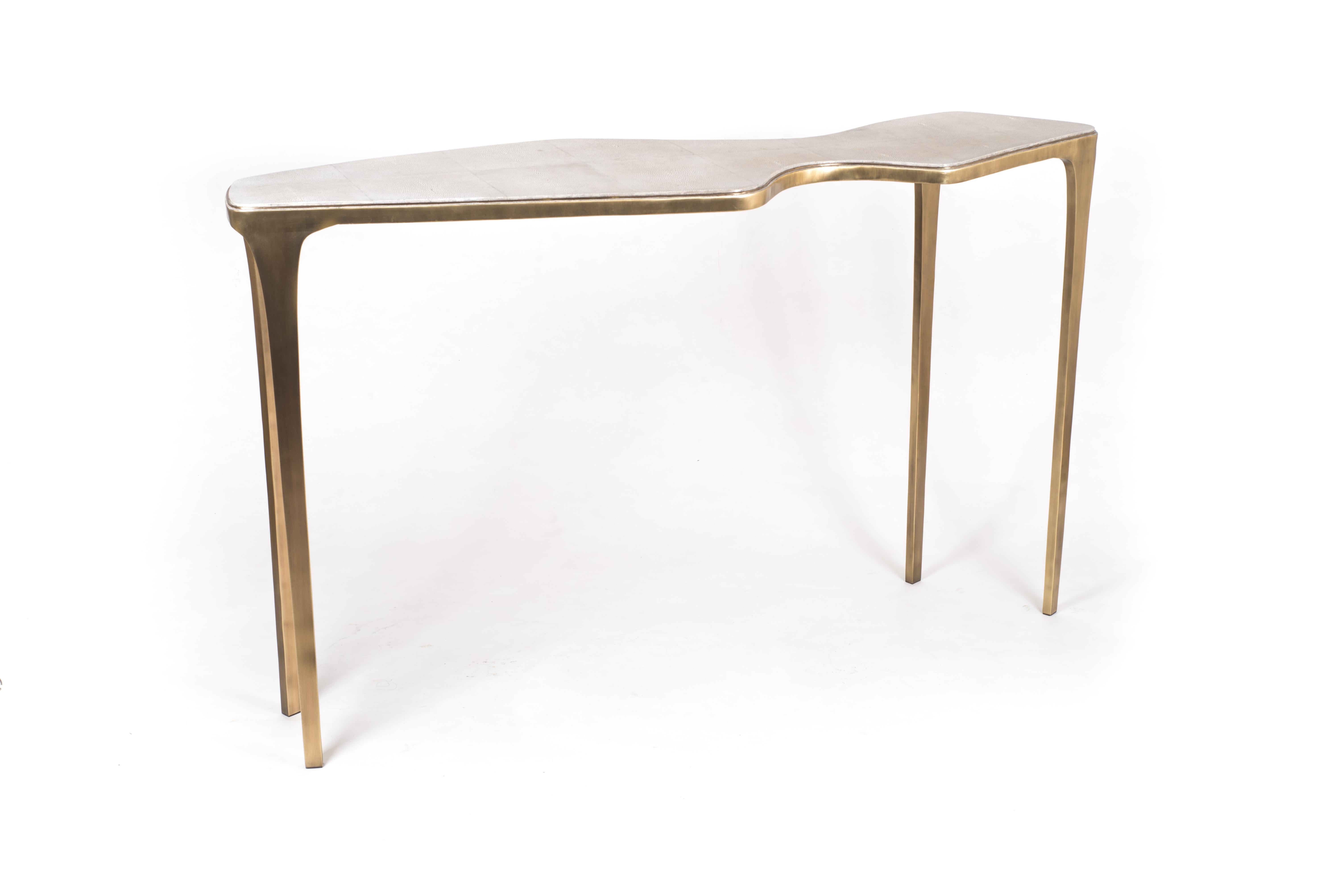 Le design simple mais élégant de la table console cosmos en fait un meuble neutre adaptable. Le plateau de forme d'inspiration cosmique en galuchat crème repose sur des pieds en laiton bronze-patiné. Couleur ou taille personnalisée disponible sur