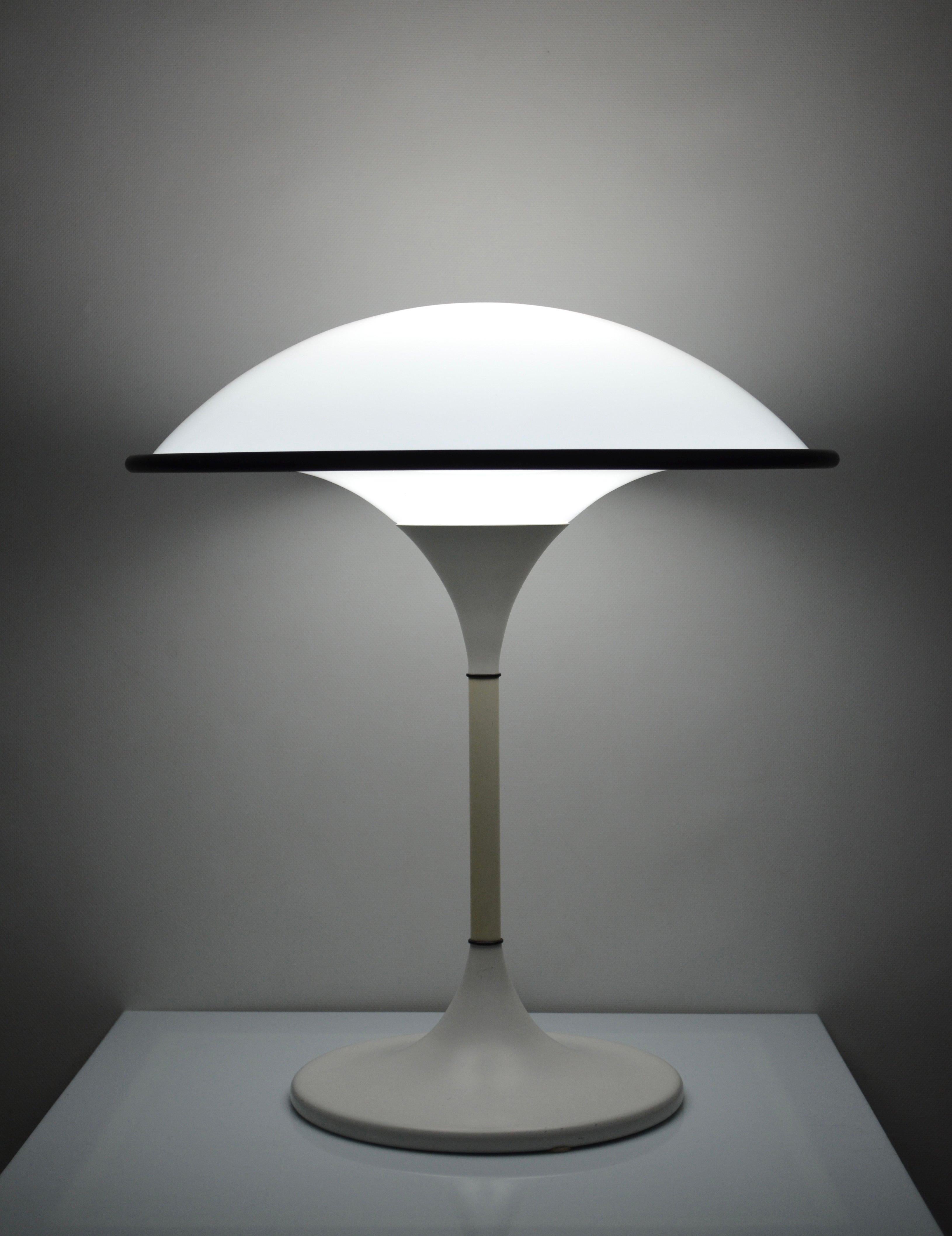 Rare ufo-shaped lamp in the Space Age style made by Preben Jacobsen for Fog Morup in 1984.
It diffuses a superb light thanks to its semi-spherical polymer diffuser underlined by its black rubber belt. 
The base is in white lacquered metal.
