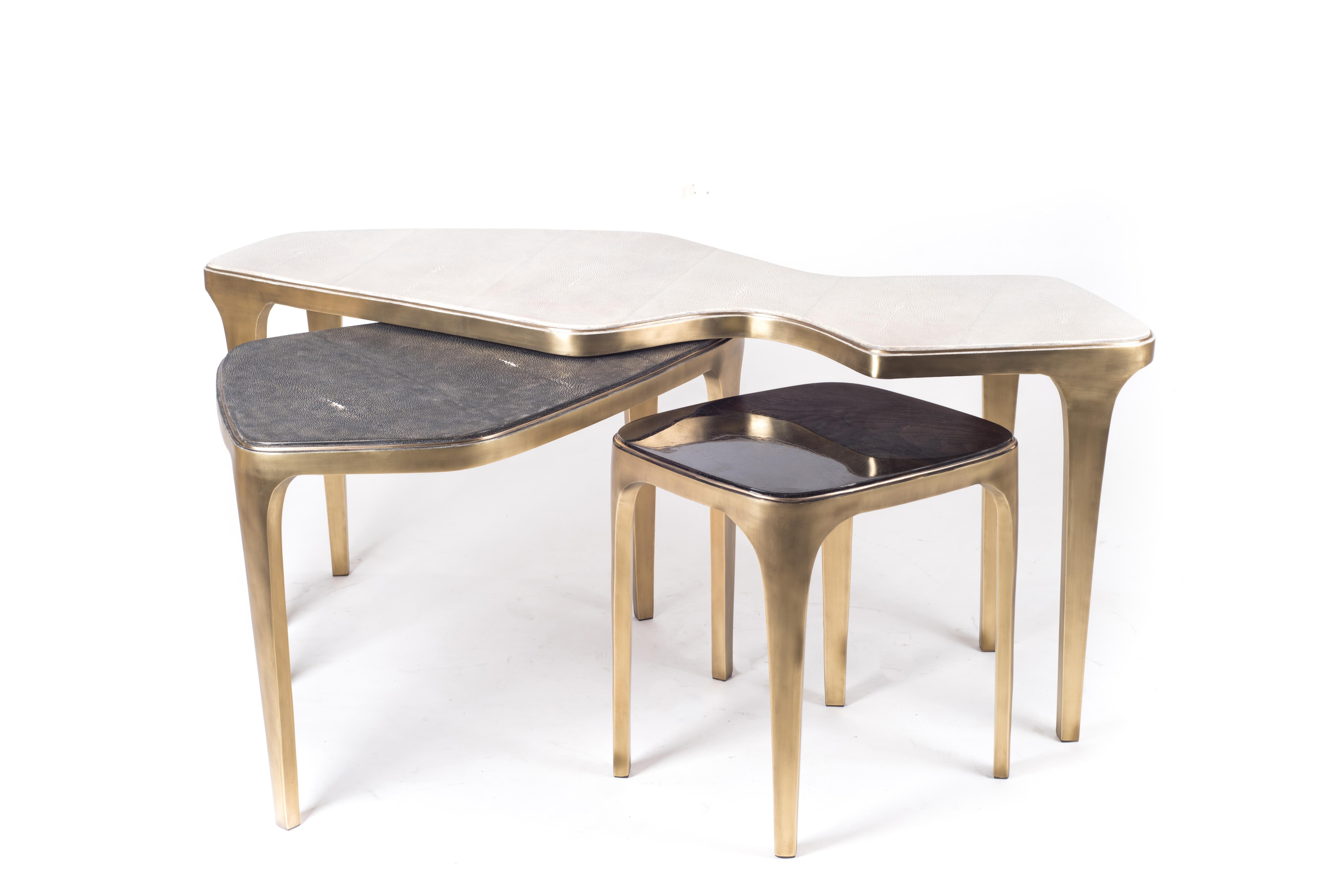 The Cosmos nesting coffee table small is both Minimalist and dramatic. The top is inlaid in black pen shell, that is hand-selected by artisans, and completed with bronze-patina brass. With its beautiful amorphous shape this piece adds a statement to