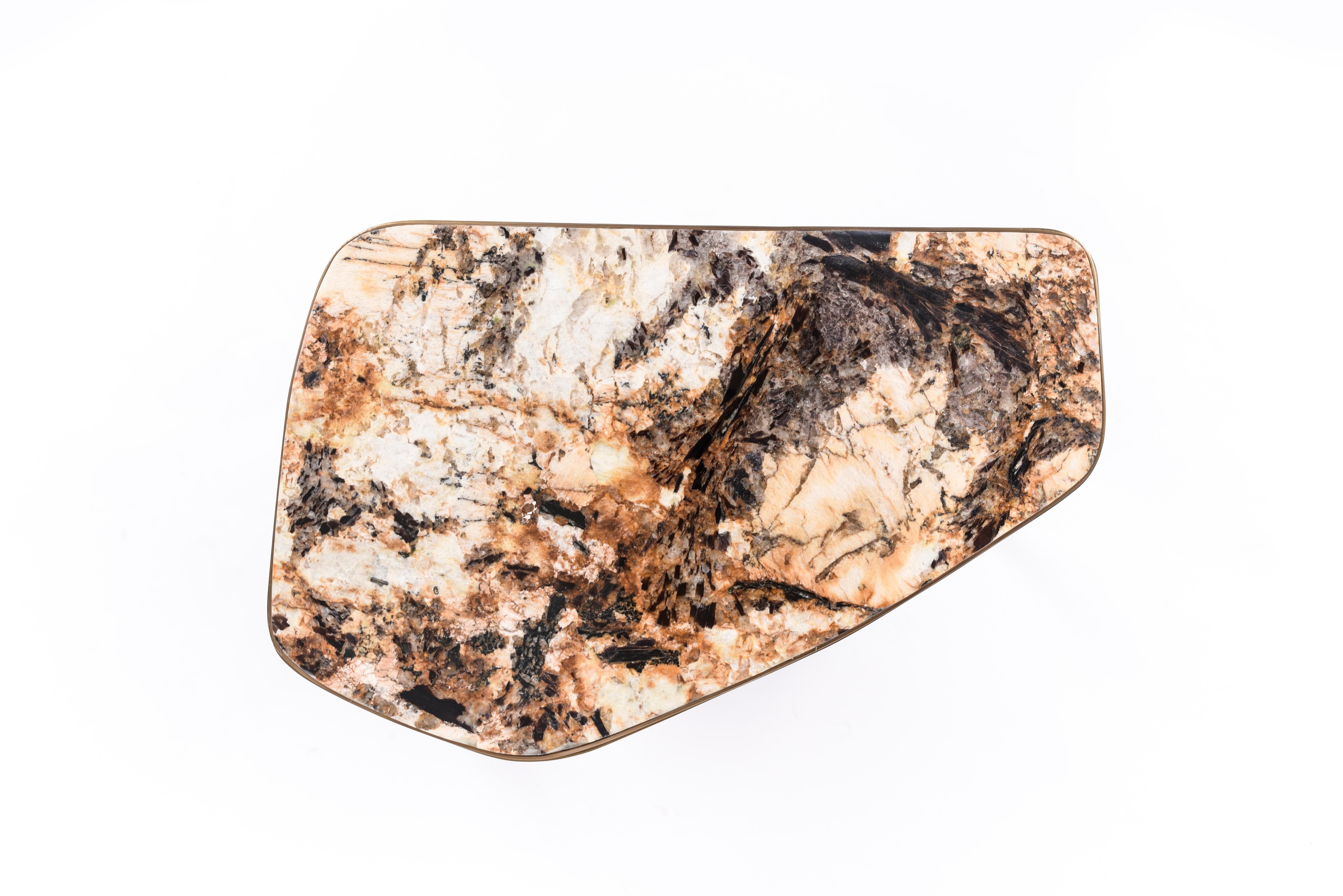 La table basse gigogne Cosmos est à la fois minimaliste et spectaculaire. Le plateau est incrusté de pierre de Hwana et complété par du laiton bronze-patiné. Le sommet de la pierre présente de belles tonalités de mélange de couleurs. Avec sa belle