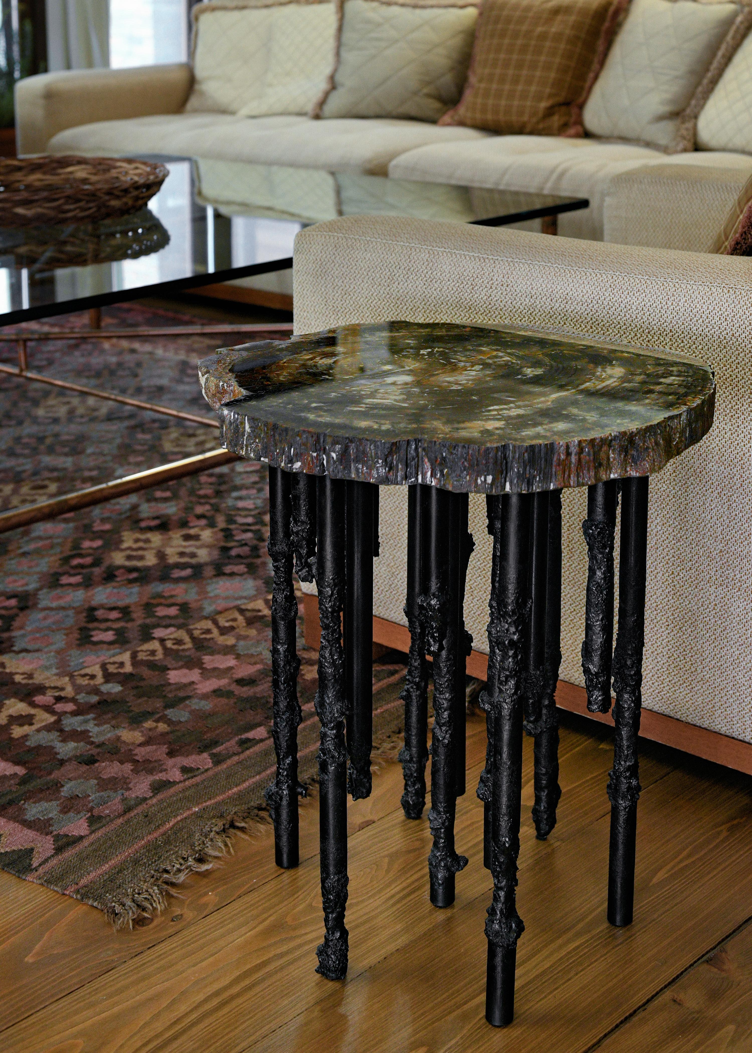 Topped with a 20 million year old slab of Arizona Petrified Wood, the Cosmos table is a unique, one of a kind sculptural side table base made with hand wrought and sculpted iron legs. Made to resemble a forest of stalactites each leg is as