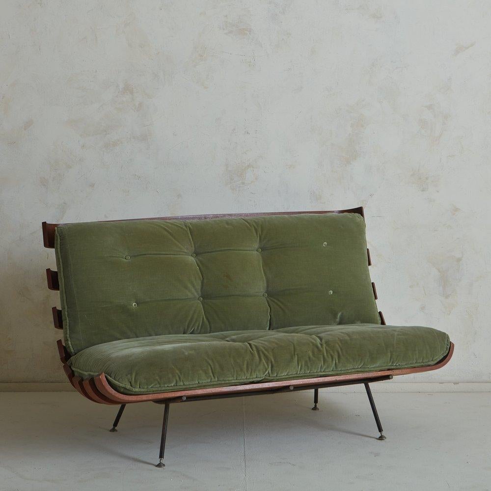 A 1960s Brazilian ‘Costela’ sofa by Martin Eisler + Carlo Hauner for Forma. This sofa features a slat wood frame with subtly curved edges and four angled, black coated steel legs with petite ball feet. It retains its original green velvet cushions