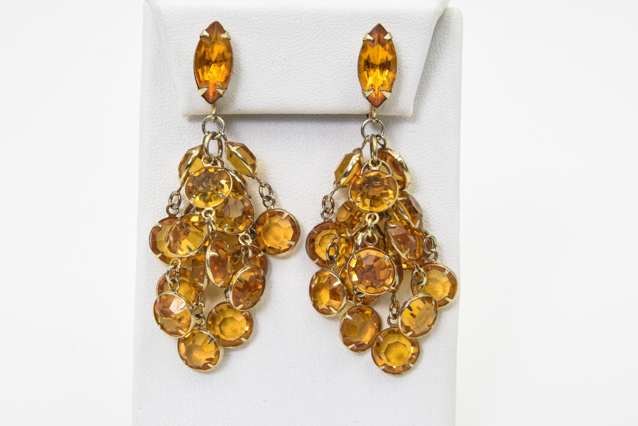 Dramatic fun earrings featuring a marquis citrine rhinestone on the ear and 9 tassels of bezel set citrine rhinestones. They have clip on backs and are not signed. The earrings measure 2.5