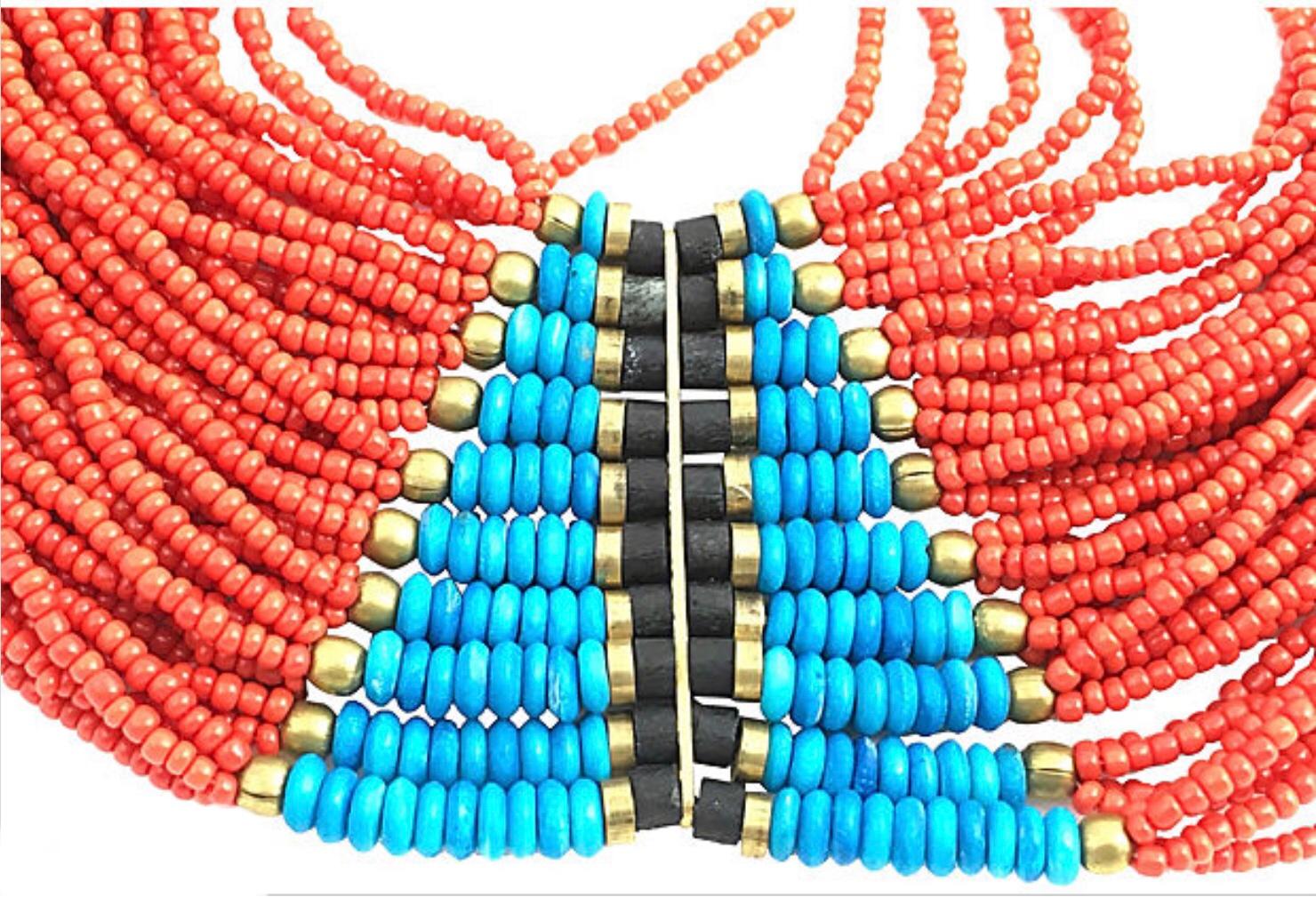 Multi-strand statement necklace featuring brass and wood accents placed between plastic turquoise- and coral-hued beads.