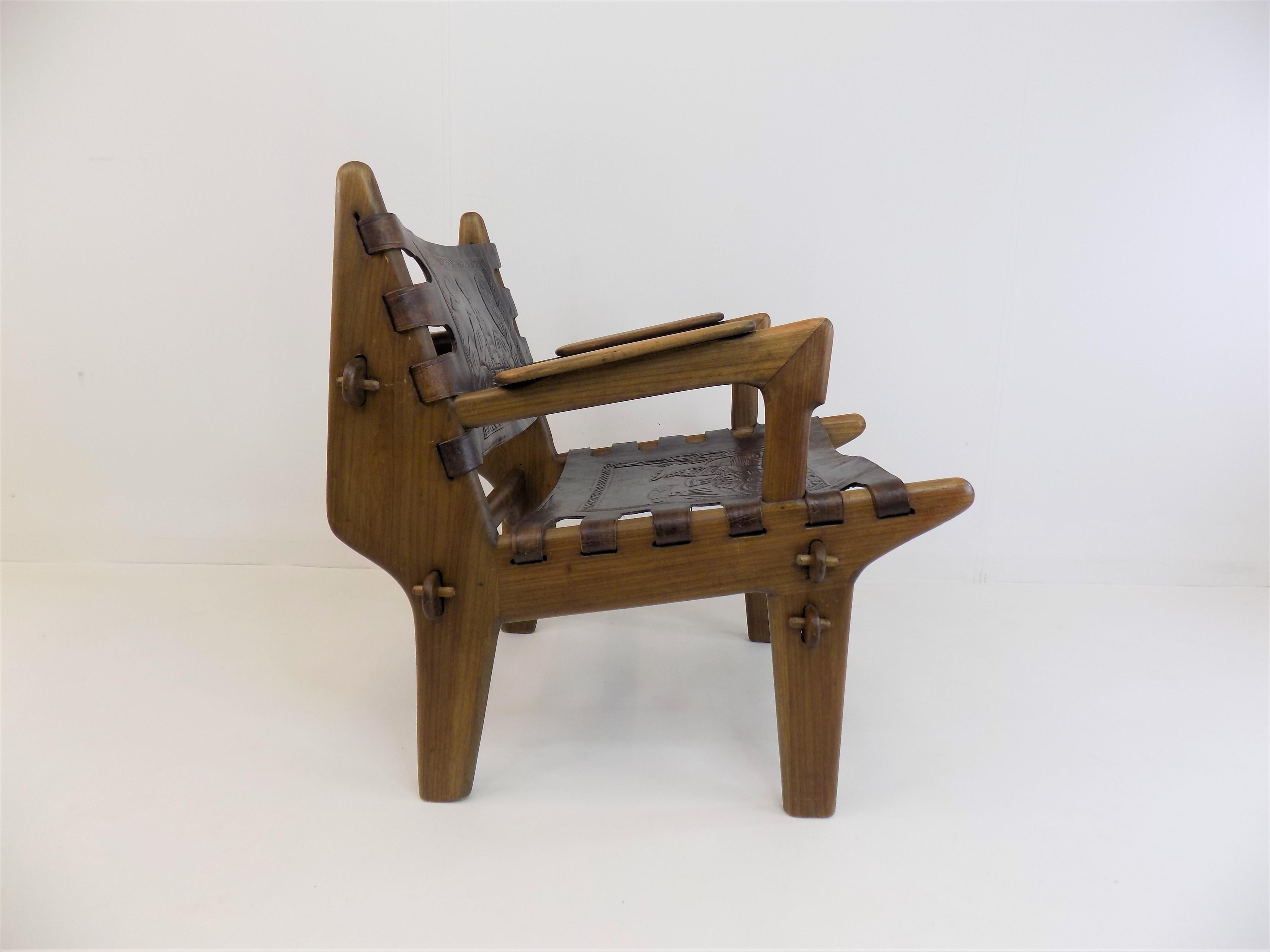 Un fauteuil en cuir Pazmino en très bon état avec un cuir foncé et un cadre en teck. Le cuir épais de la selle montre des scènes de paysage dans les Andes et est en très bon état. Le cadre est très solide et ne présente pratiquement aucun signe
