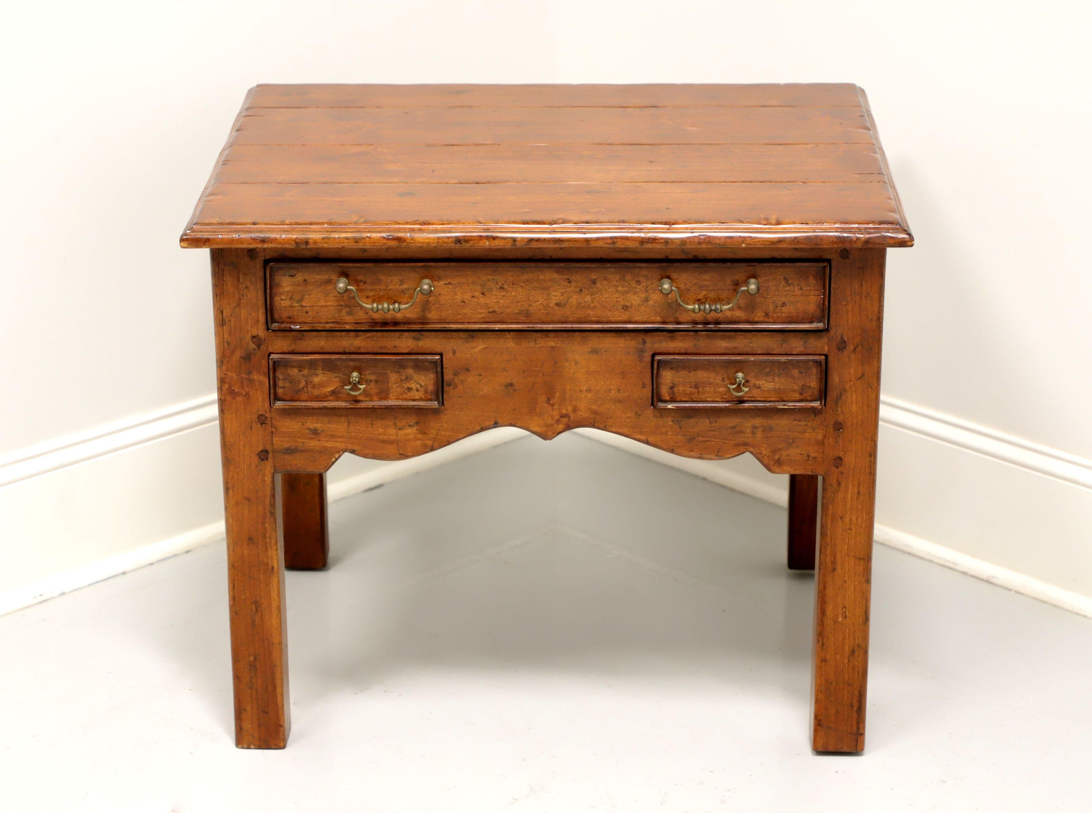 A Cottage Rustic style side table, unbranded, similar quality to Century Furniture. Walnut with a distressed finish, plank style top, brass hardware, carved apron and straight legs. Features one larger over two smaller dovetailed drawers. Made in