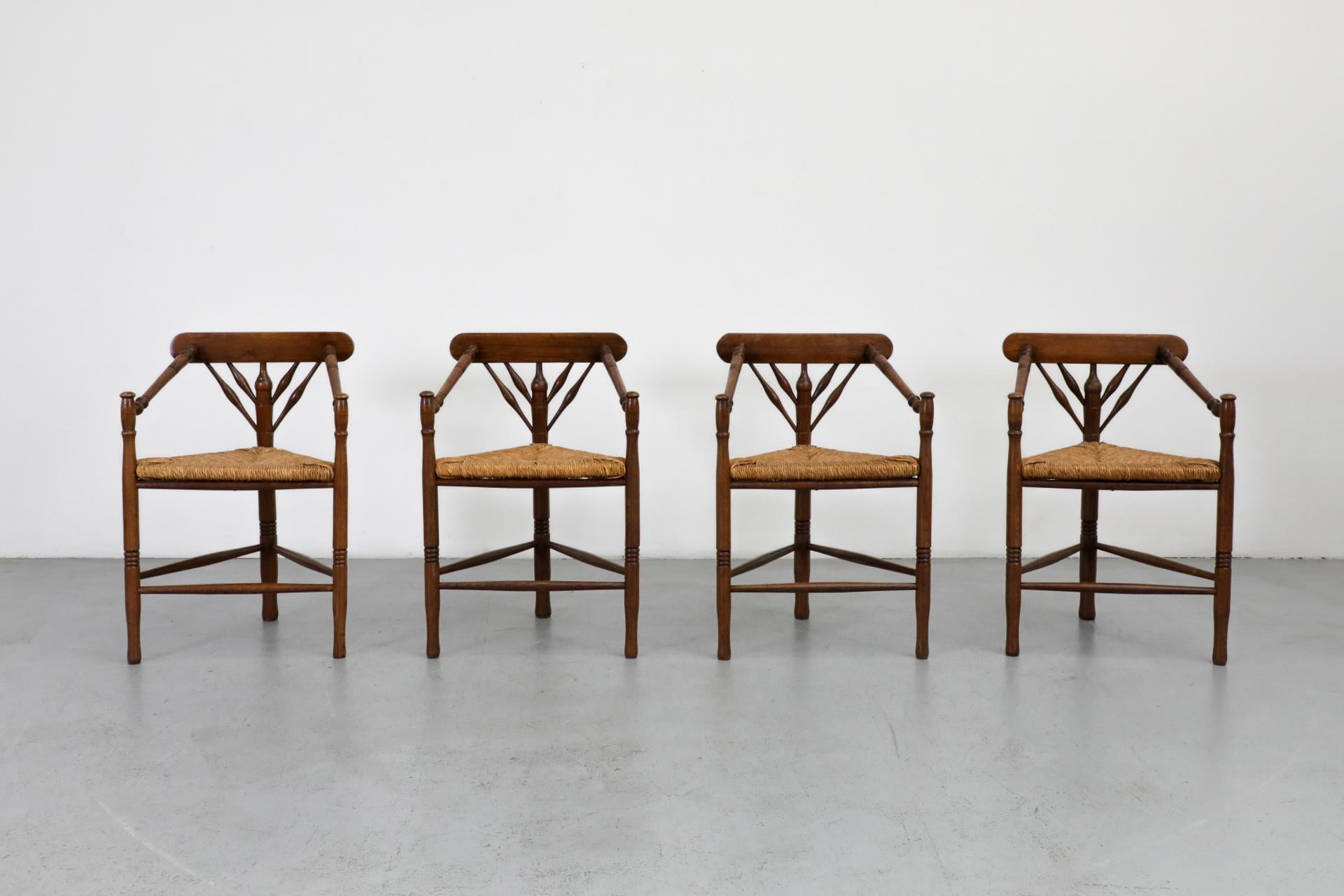 Cottage style dining chairs with triangular rattan seats, three legs and beautifully carved inverse triangle backrest. In original condition with visible wear, including some rattan breakage, consistent with their age and use. Priced individually.