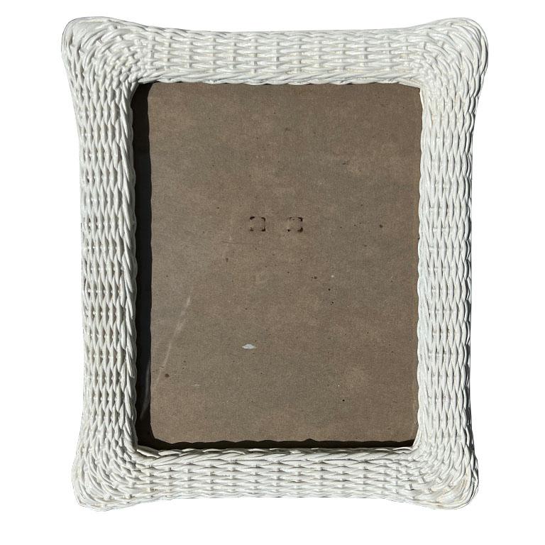 Un portafoto alto in finto vimini. Questa cornice vintage sarà perfetta su un tavolino o un comodino. È realizzato in gesso o in legno e ricorda la trama del vimini intrecciato. Gli angoli sono arrotondati e una lastra di vetro copre la parte