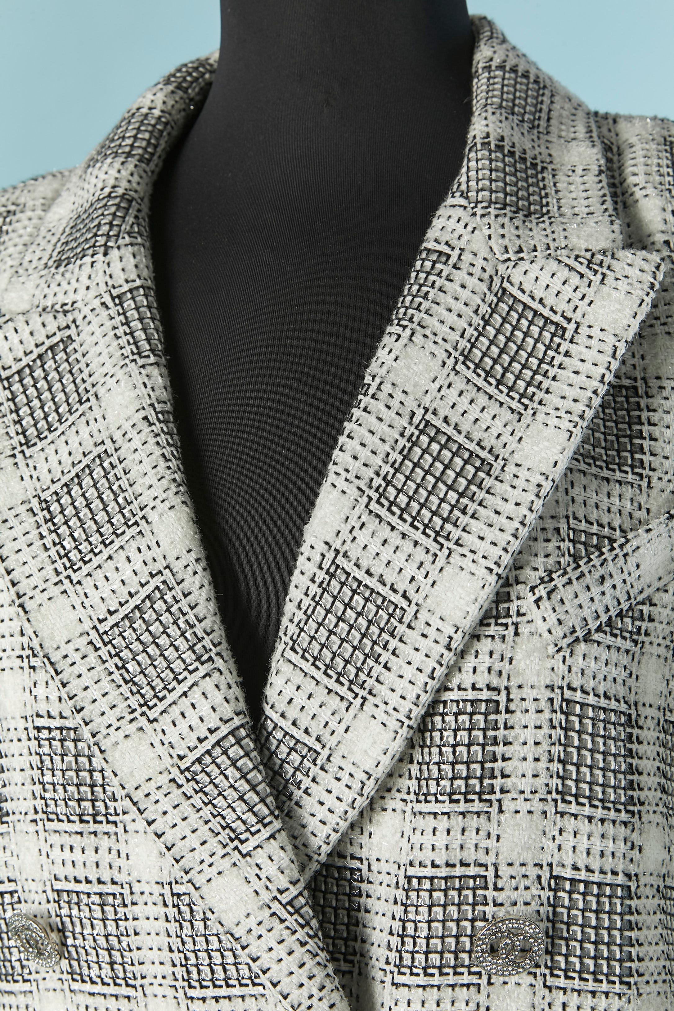 Giacca doppiopetto in tweed di cotone e nylon. Composizione del tessuto principale: 55% cotone, 11% nylon, 20% poliestere, 14% acrilico. Fodera in seta . 
Chiusura con bottoni e asole di strass sul centro davanti e sui polsini. 
Spallaccio. Tasca su
