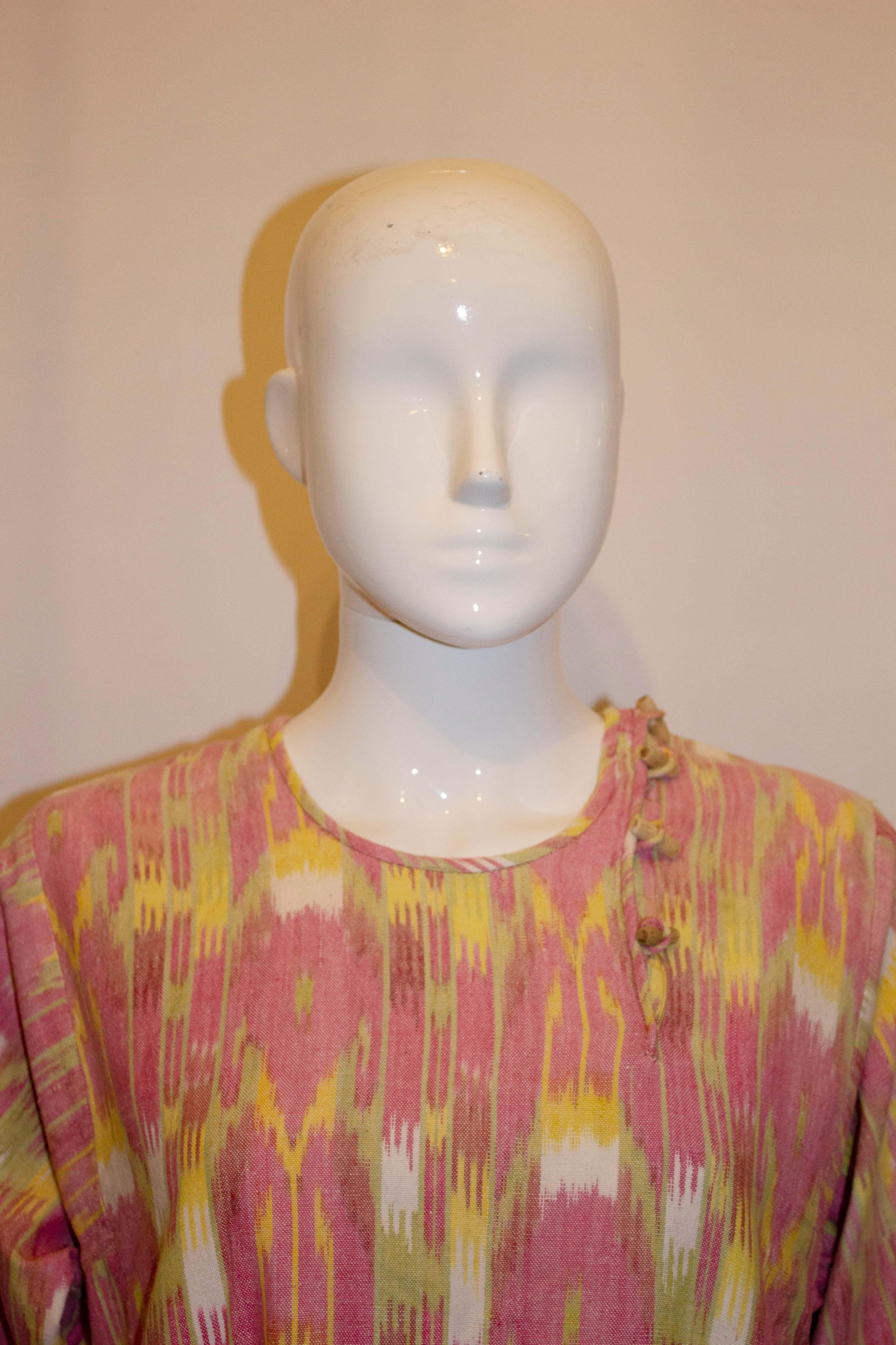 A pretty Ikat dress in a raspberry , white and yellow mix. The dress has a round neck and fastens on the shoulder and has elbow length sleaves. Measurements: Bust up to 41'',length 44''  with 13'' slits on either side. 