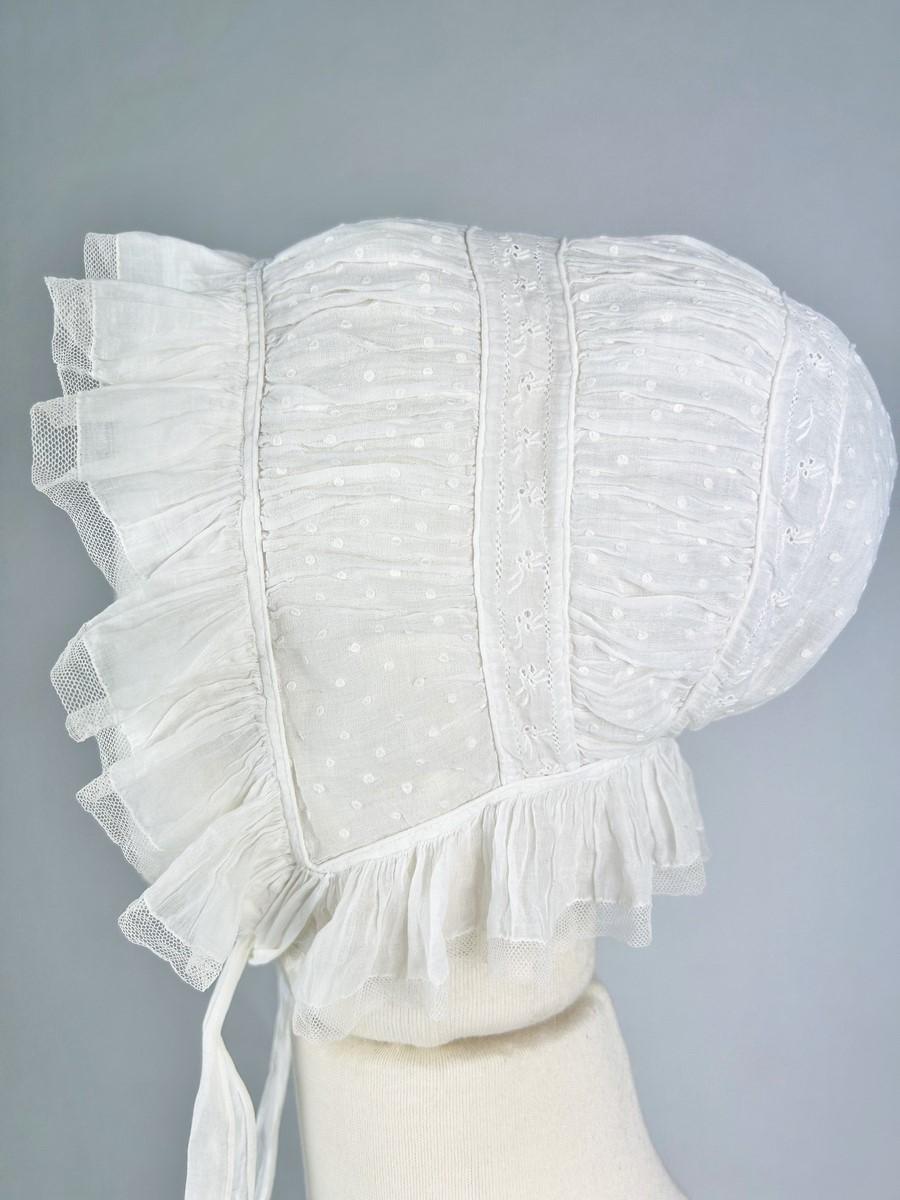 Circa 1810/1840
Francia o Provenza
Interessante CAP in mussola di cotone ricamato con plumetis. Una cuffietta a forma di conchiglia, come si vede nell'iconografia regionale dei primi decenni del XIX secolo, composta da due passate di broderie