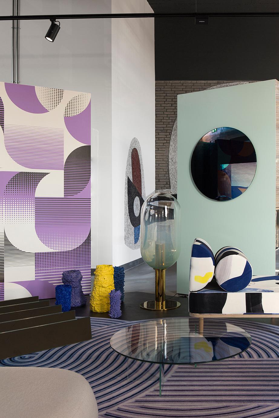 A large mirror reflecting through various swatches of color. The mirror offers a wide range of colours from light to dark swerve. The mirror is organised in an even concentric block pattern. The reflection of the mirror makes each color multiply