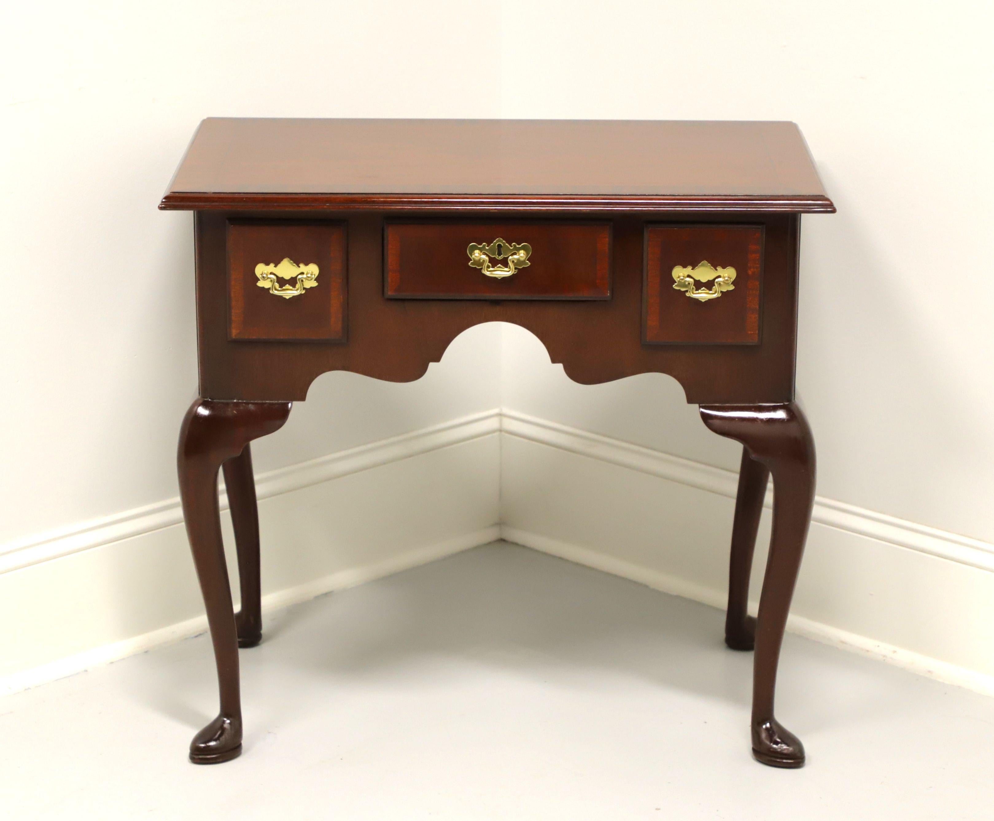 A Queen Anne style side table by Councill. Mahogany with banded top & drawer fronts, brass hardware, carved apron, cabriole legs and pad feet. Features three drawers of dovetail construction, center one having a faux keyhole escutcheon. Made in