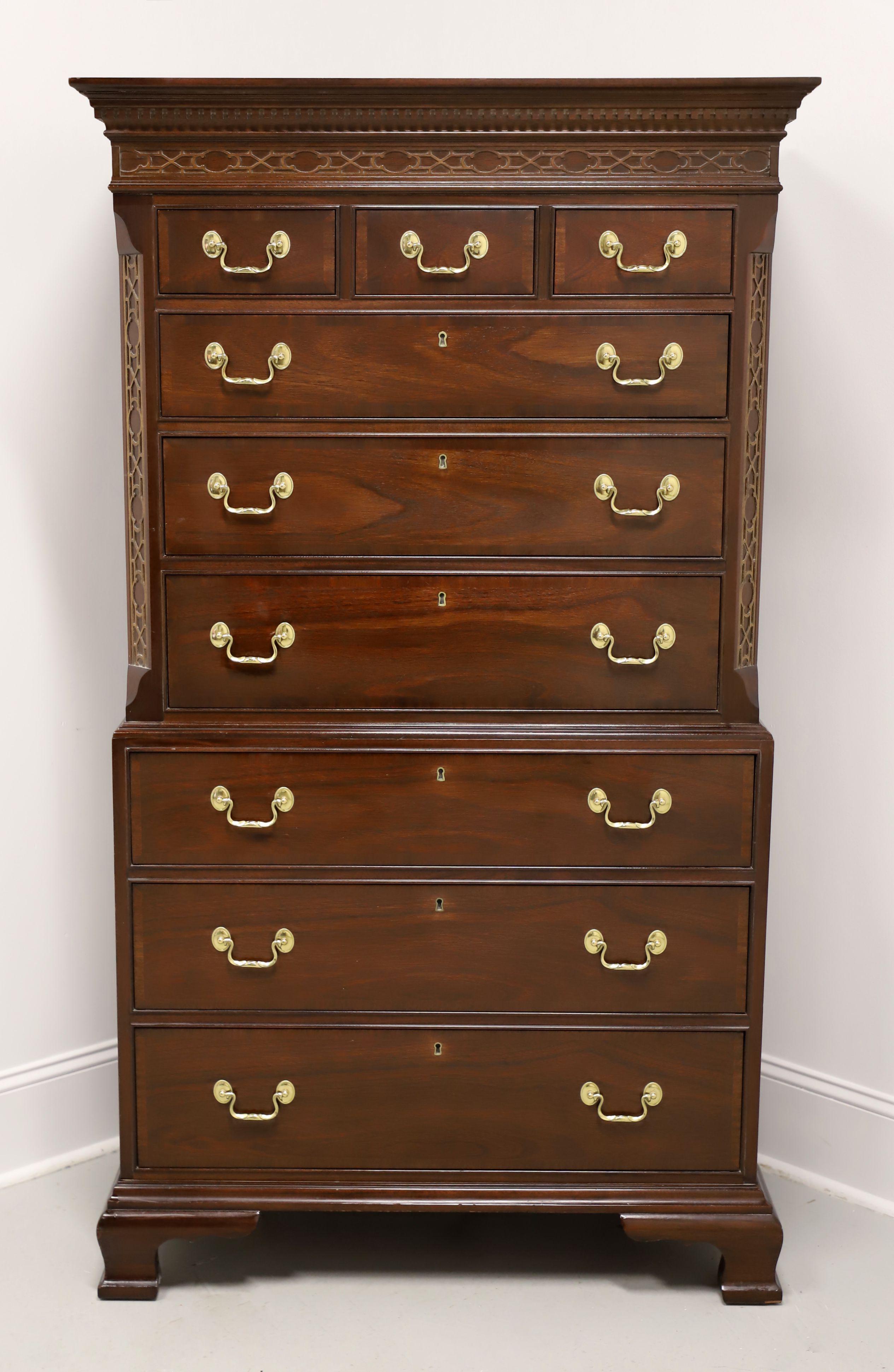 A Chippendale style chest on chest of drawers by Councill Craftsmen. Mahogany with brass hardware, mitre edge to top, crown & dentil moulding with carved blind fretwork frieze, banded drawer fronts, decorative carved blind fretwork to canted corners