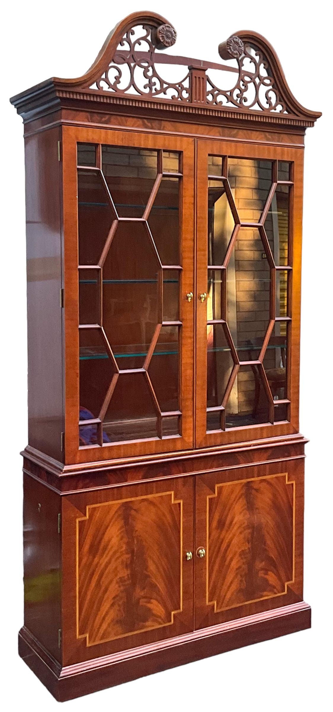 This is a beautiful pair of Chinese Chippendale style flame mahogany display cabinets by Councill Craftsmen. They have interior glass shelves that are illuminated by two lights. The base has a single wooden shelf. They are marked and date to the