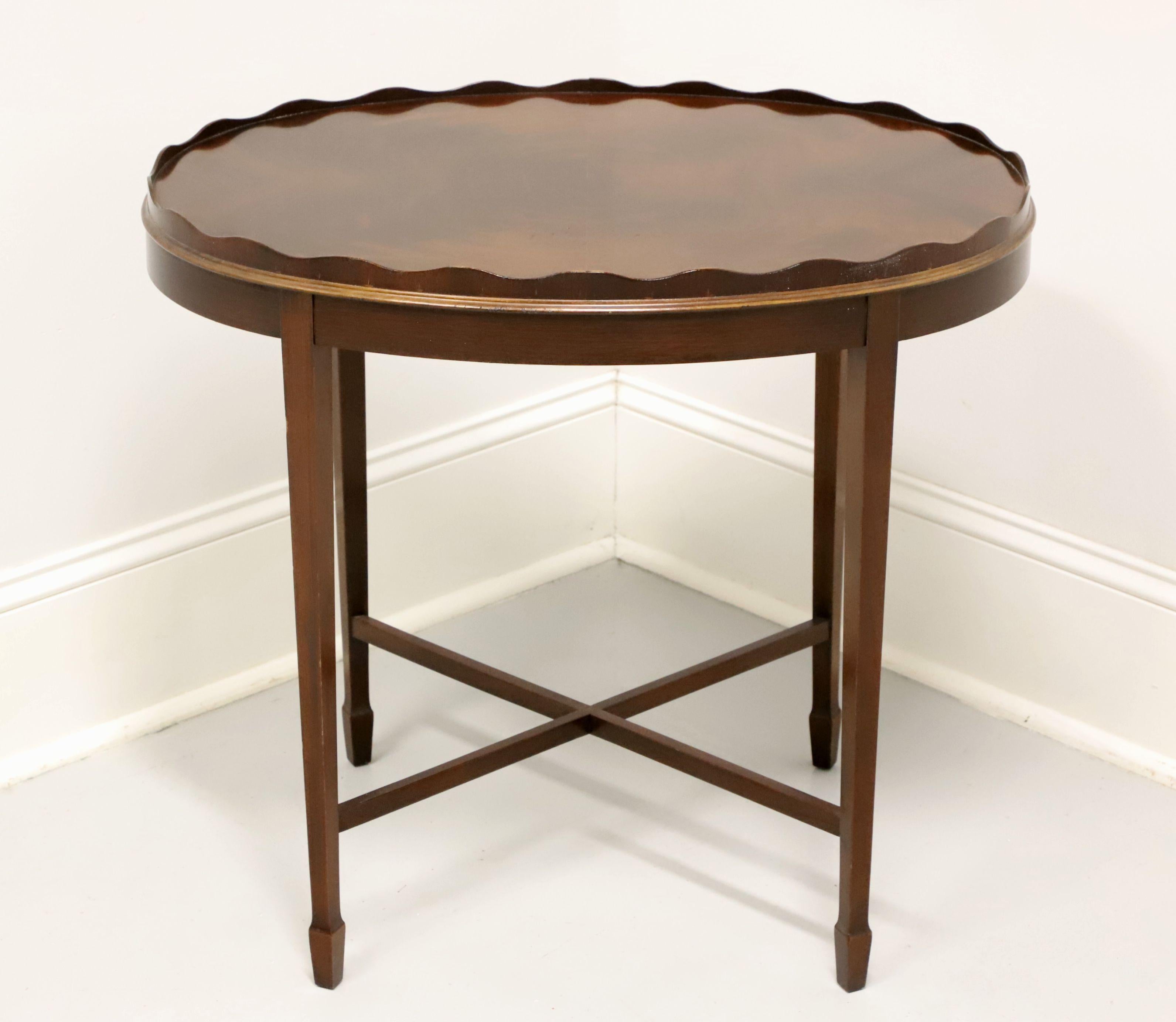 A Traditional style oval side table by Councill Craftsmen. Mahogany with a flame mahogany top, raised scalloped edge, stretchers and tapered straight legs with spade feet. Made in North Carolina, USA, in the late 20th century.

Measures: 20 W 27 D