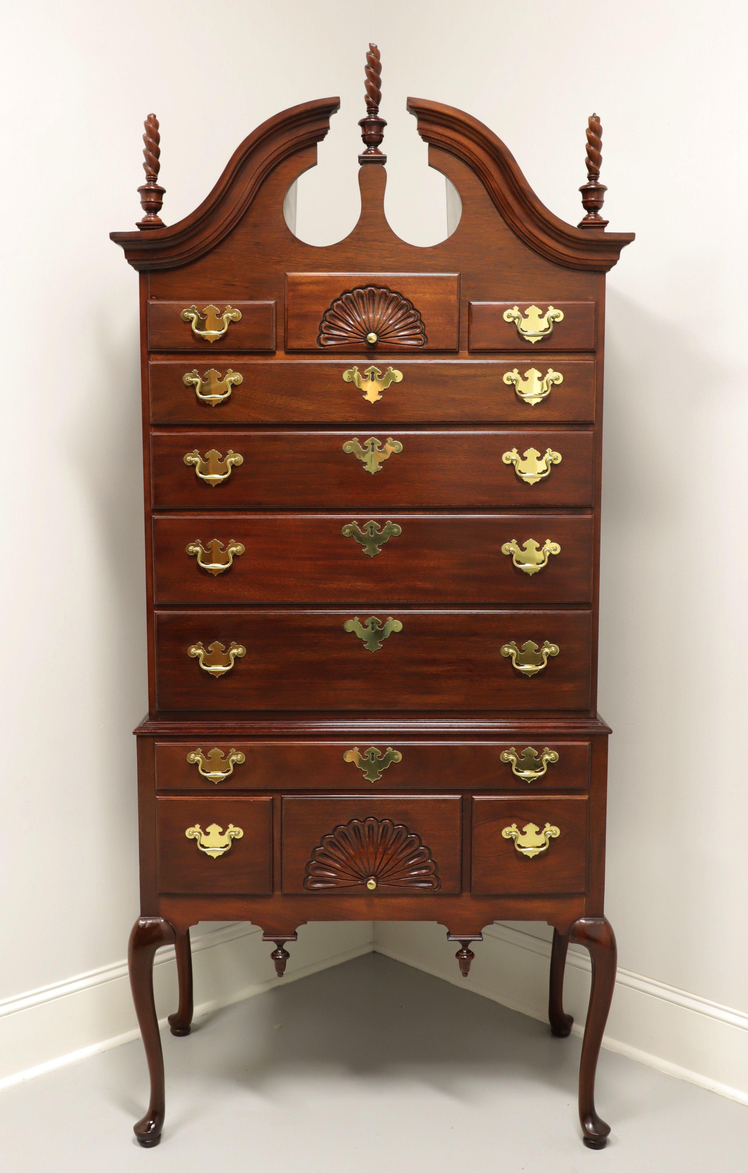 A Queen Anne style highboy chest by Councill Craftsmen. Mahogany with brass hardware, broken bonnet top with center & side plume form finials, open fan carvings to two drawers, carved reverse finials to apron, cabriole legs and pad feet. Features