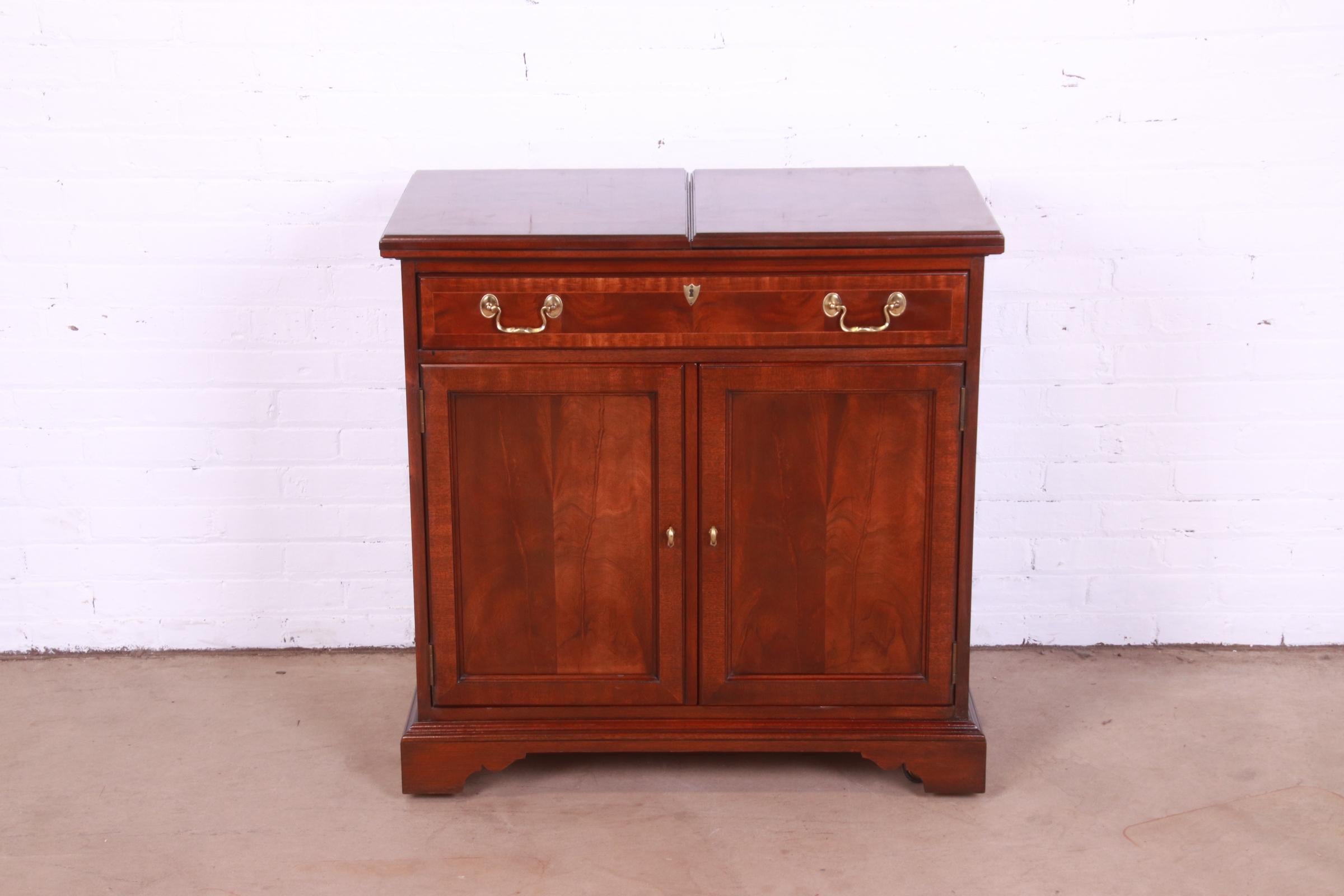 An exceptional Georgian or Chippendale style rolling bar cart or bar cabinet server

By Councill Furniture

USA, Circa 1980s

Banded flame mahogany, with original brass hardware.

Measures: 34