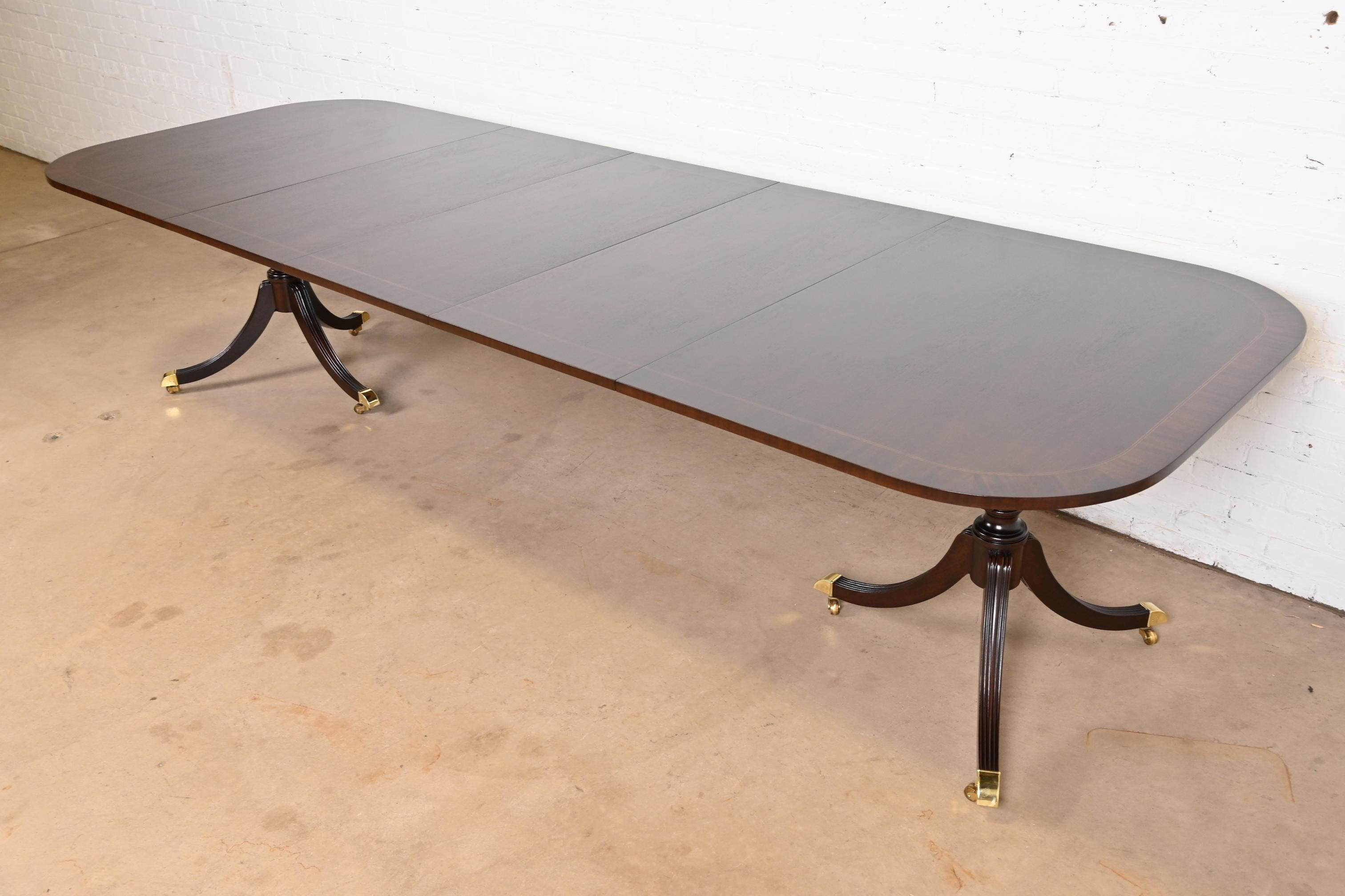 Exceptionnelle table à manger à rallonge à double piédestal de style Géorgien ou Régence.

Par Councill Furniture

USA, Circa 1980

Magnifique acajou, avec incrustation de cordes en bois de satin, piédestaux en acajou massif sculpté, et pieds