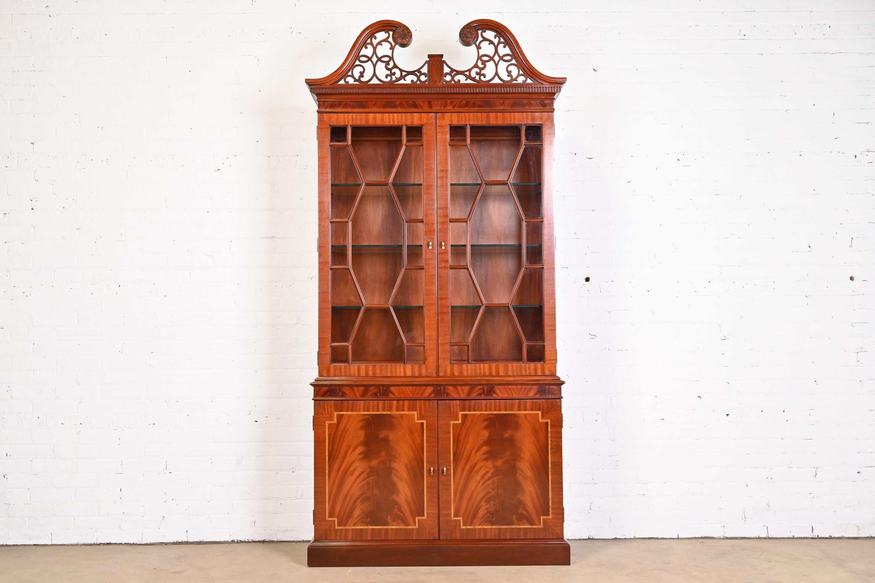 An exceptional Georgian or Chippendale style lighted breakfront bookcase cabinet

By Councill Furniture

USA, Circa 1980s

Book-matched flame mahogany, with satinwood inlay, mullioned glass front doors, and original brass