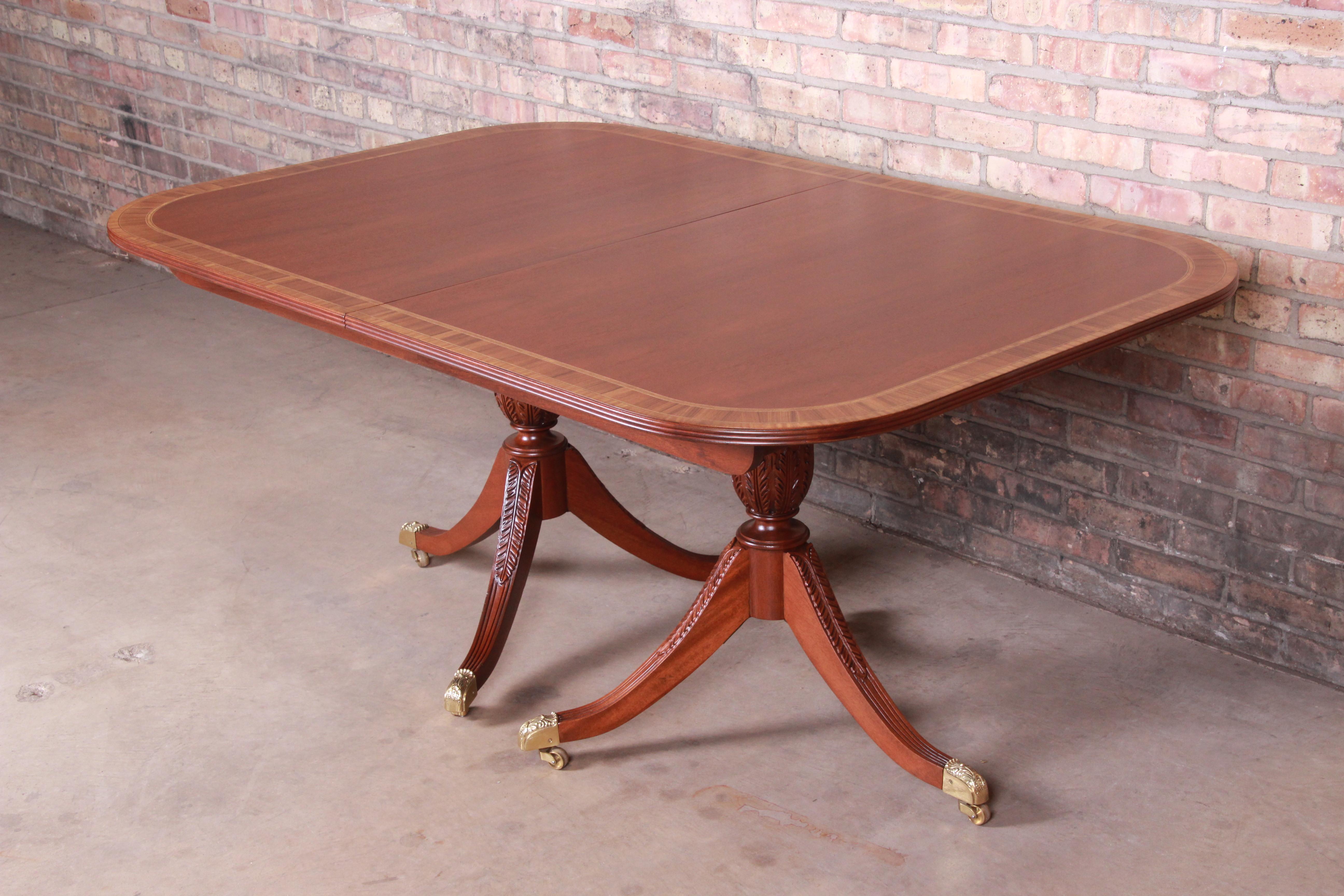 An exceptional Georgian style extension double pedestal dining table

By Councill Furniture

USA, circa 1980s

Bookmatched mahogany with inlaid satinwood banding, carved solid mahogany pedestals, and brass-capped feet.

Measures: 64.13